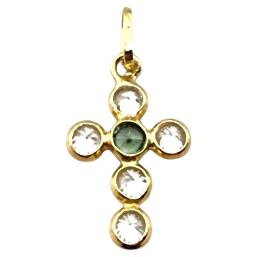 Ciondolo a forma di croce in oro giallo 18 carati con castone e pietre incastonate.

Questo ciondolo a croce in oro giallo 18 carati presenta una finitura lucida e pietre colorate (verdi e bianche) incastonate che aggiungono dettagli vibranti al