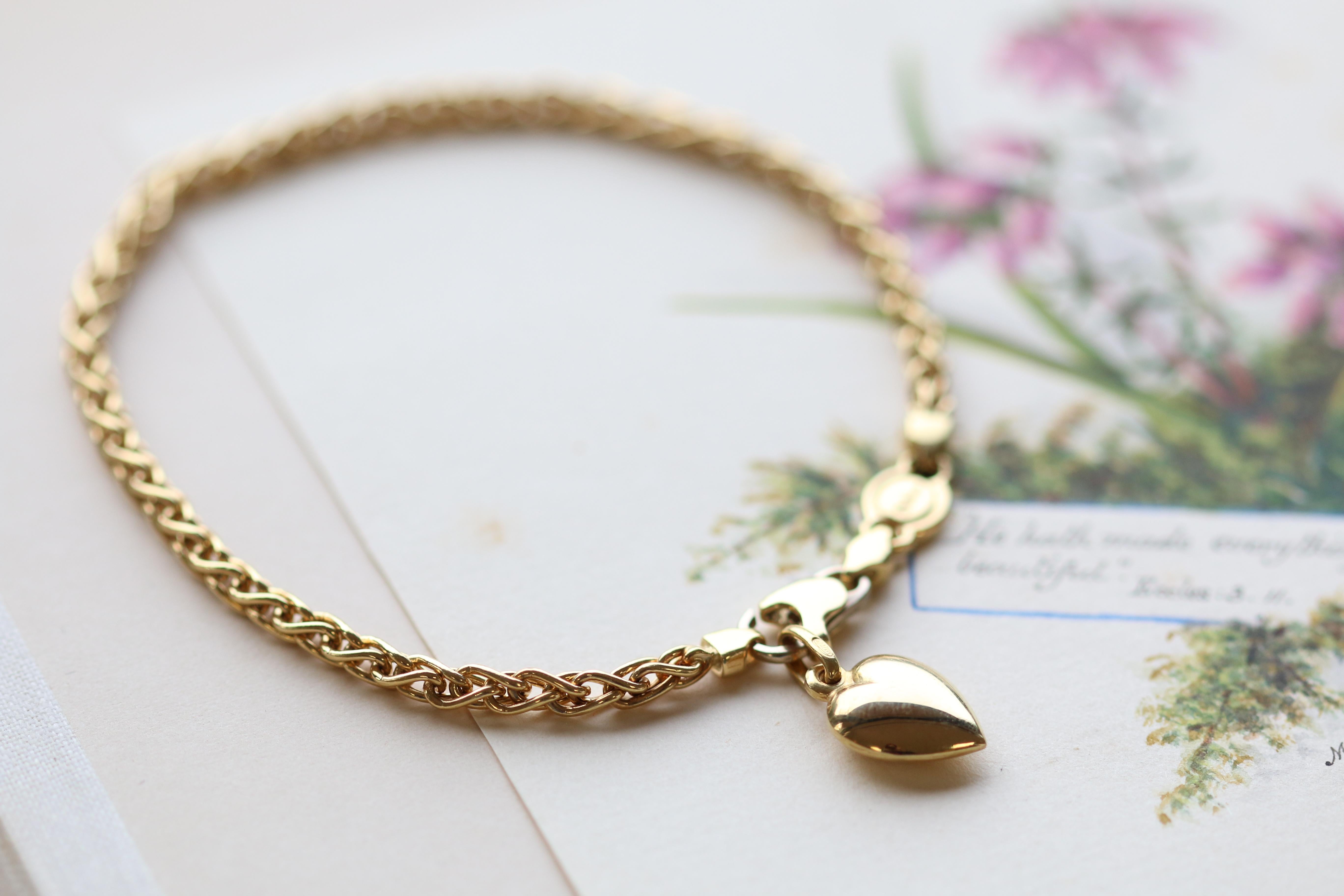 A sweet, and simply stunning 18K gold bracelet. A delicate heart pendant hangs on the clasp. Therefore giving the bracelet added style. It hangs effortlessly on the bracelet providing it with both graceful beauty and added movement. The warm glow of