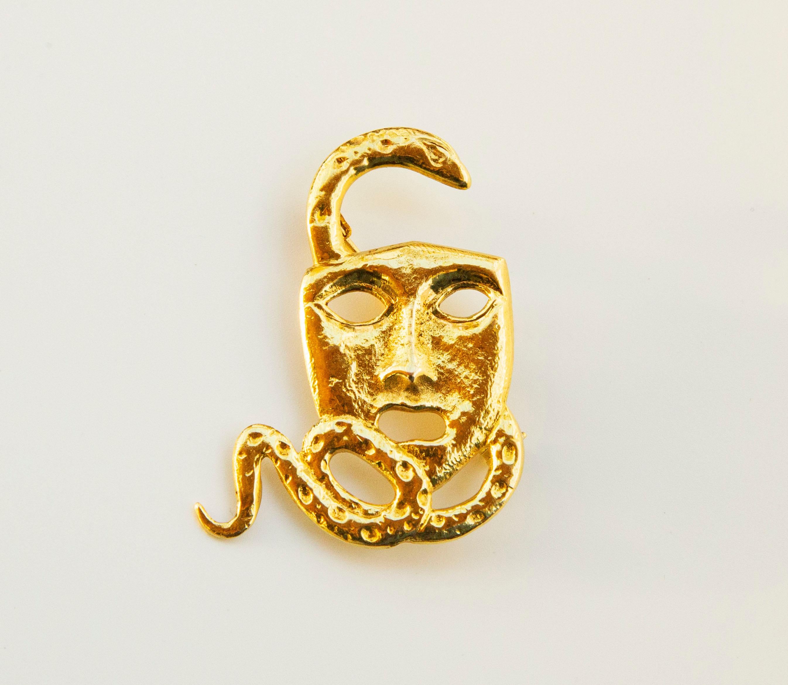 A 18 karat yellow gold designed as an actor/drama/theater mask with a snake. The mask features a textured and hammered front surface while the back side of the mask is smooth. The brooch was manufactured in late 20th century in the Netherlands.  The
