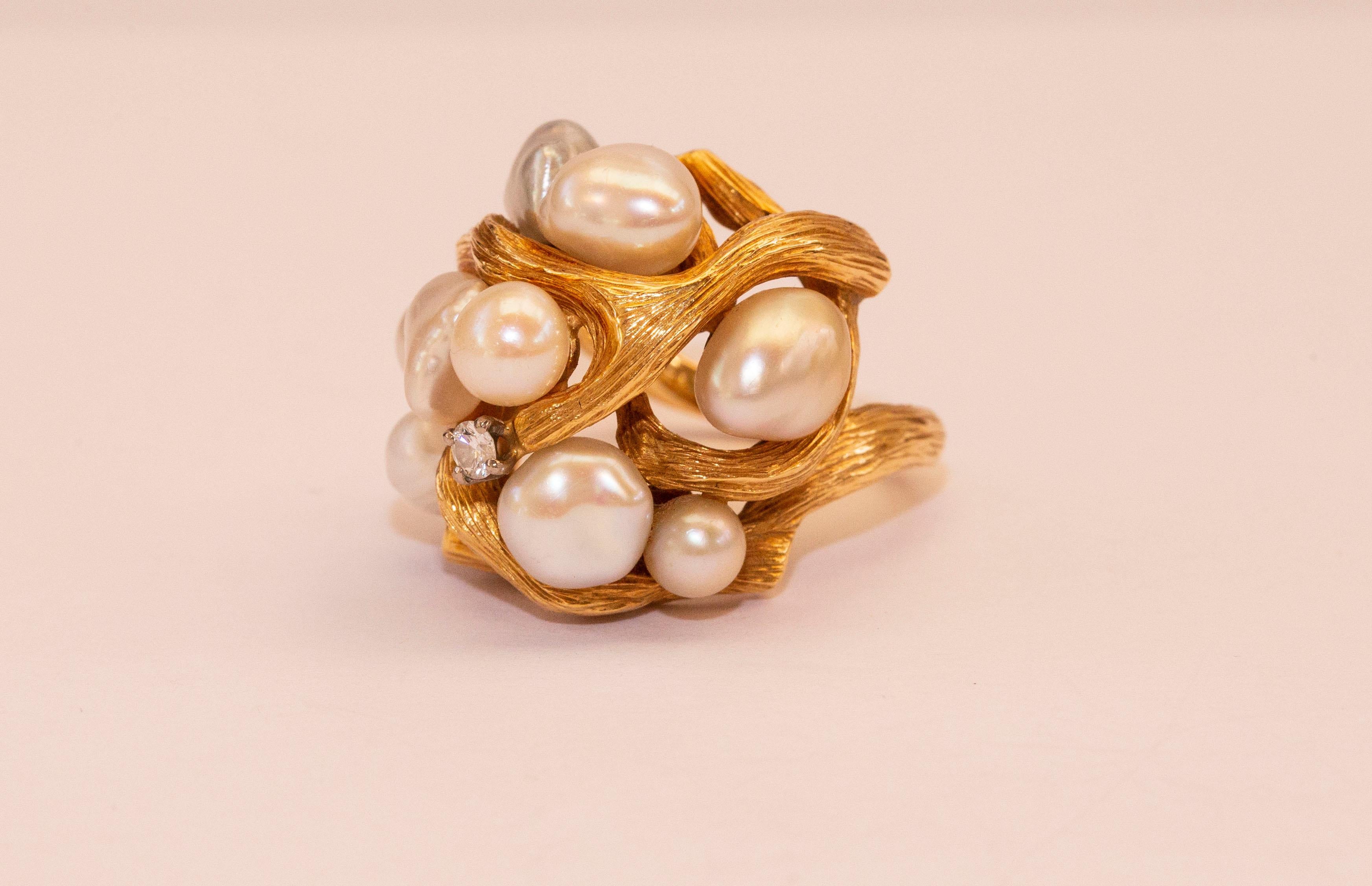 A vintage 18 karat yellow gold cocktail ring with cultivated pearls and a diamond. The ring features a textured organic golden frame with trapped irregular shaped pearls and a diamond on the top. The pearls have grayish and creamy color. It is a