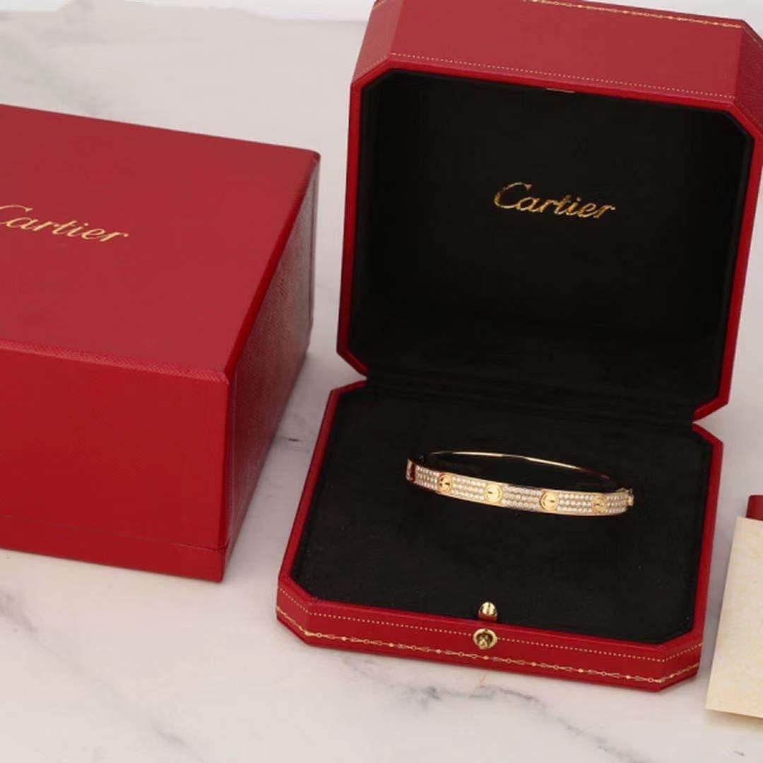 The iconic authentic Cartier LOVE bracelet made in 18K yellow gold with 204 brilliant-cut diamonds weighing 2.00 carats. The timeless design has a soft oval shape with gold nail heads. This bracelet is hinged and features a safety latch and