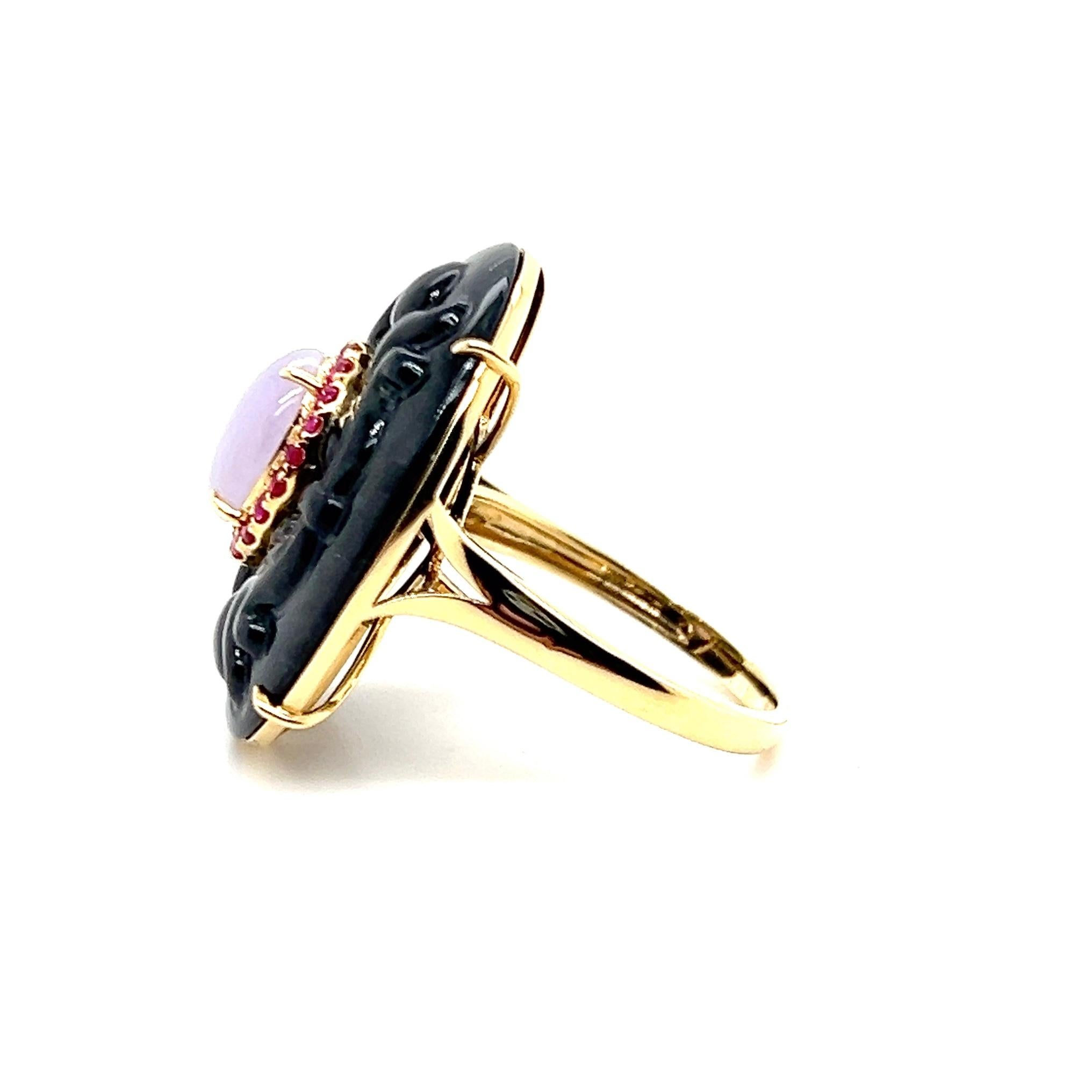 Une bague de cocktail en or jaune 18 carats avec une pièce centrale en onyx sculpté de forme ovale mesurant 26 x 21,5 mm. Au centre se trouve un cabochon ovale de jadéite lavande mesurant 9 x 7 mm, entouré d'un délicat halo de vingt rubis rouges