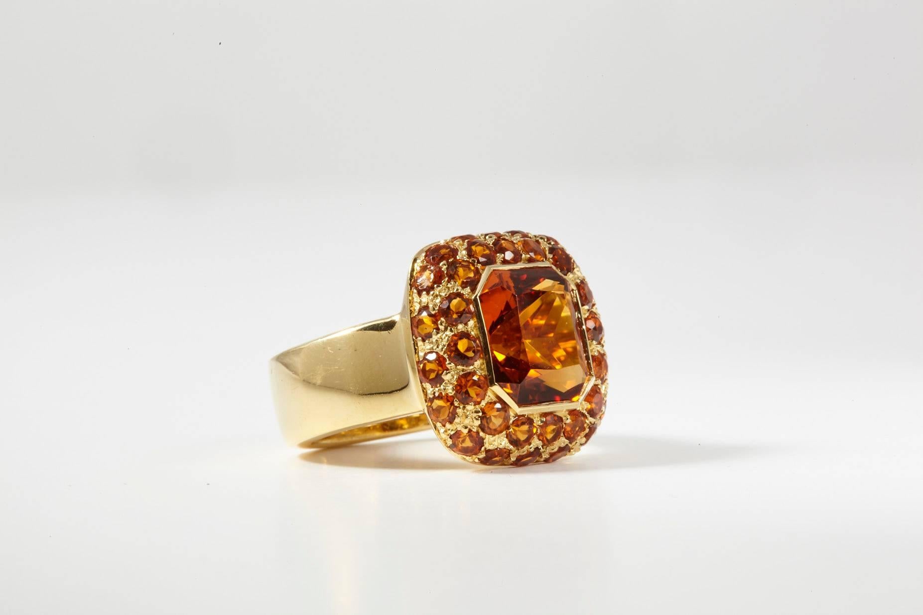Italian Made 18 Karat Yellow Gold Citrine Cocktail Ring, featuring cushion cut center stone surrounded by two layers of 45 citrine round brilliant stones. The deep hue of the citrine orange color can't be ignored.  It's a contemporary design with a