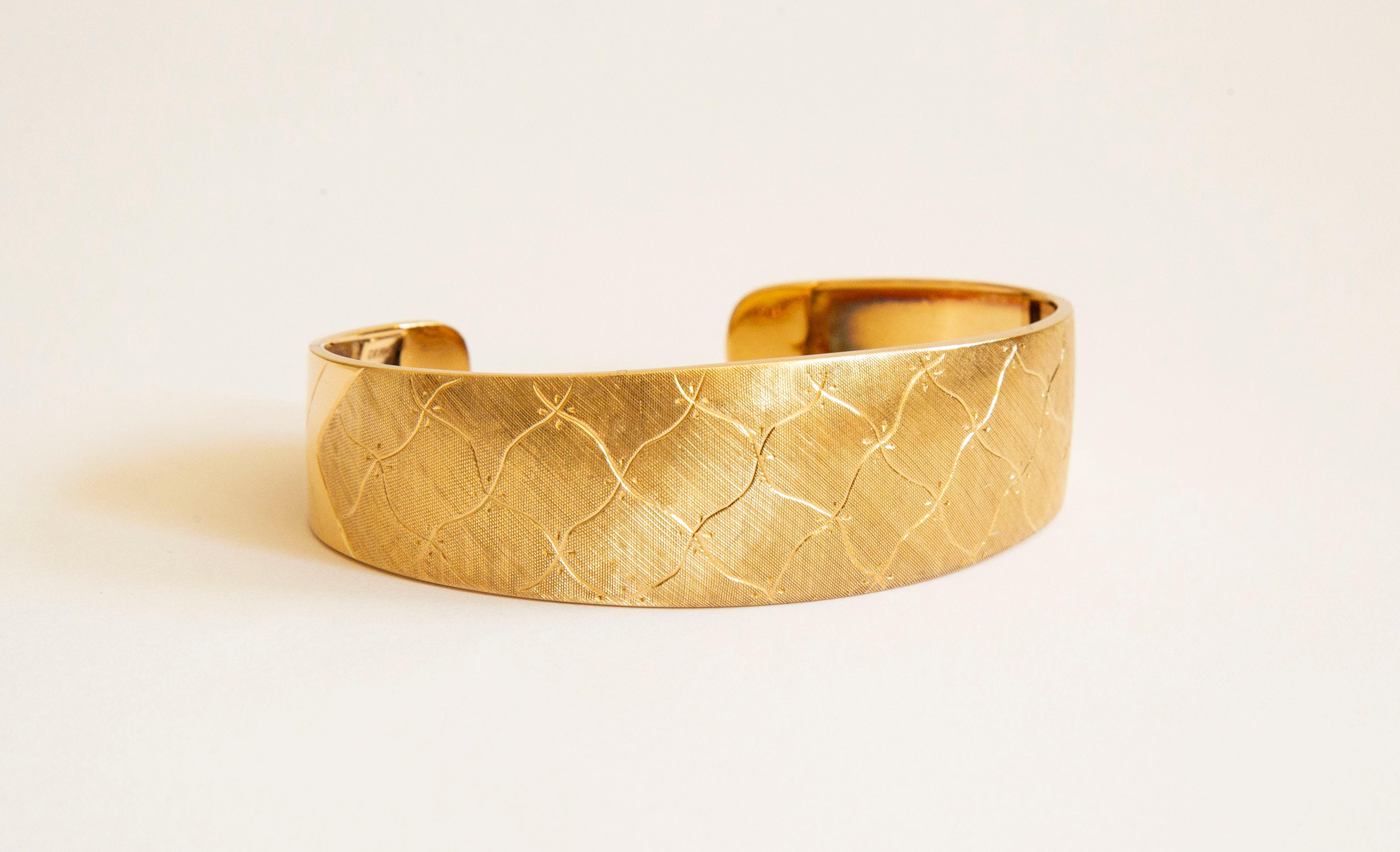 Ein Manschettenarmband aus 18 Karat Gelbgold. Das Armband ist mit einem abstrakten und unregelmäßigen Diamantenmuster graviert und hat eine satinierte/matte Oberfläche. Das Muster und das Finish bedecken die Oberseite und teilweise die Seitenteile