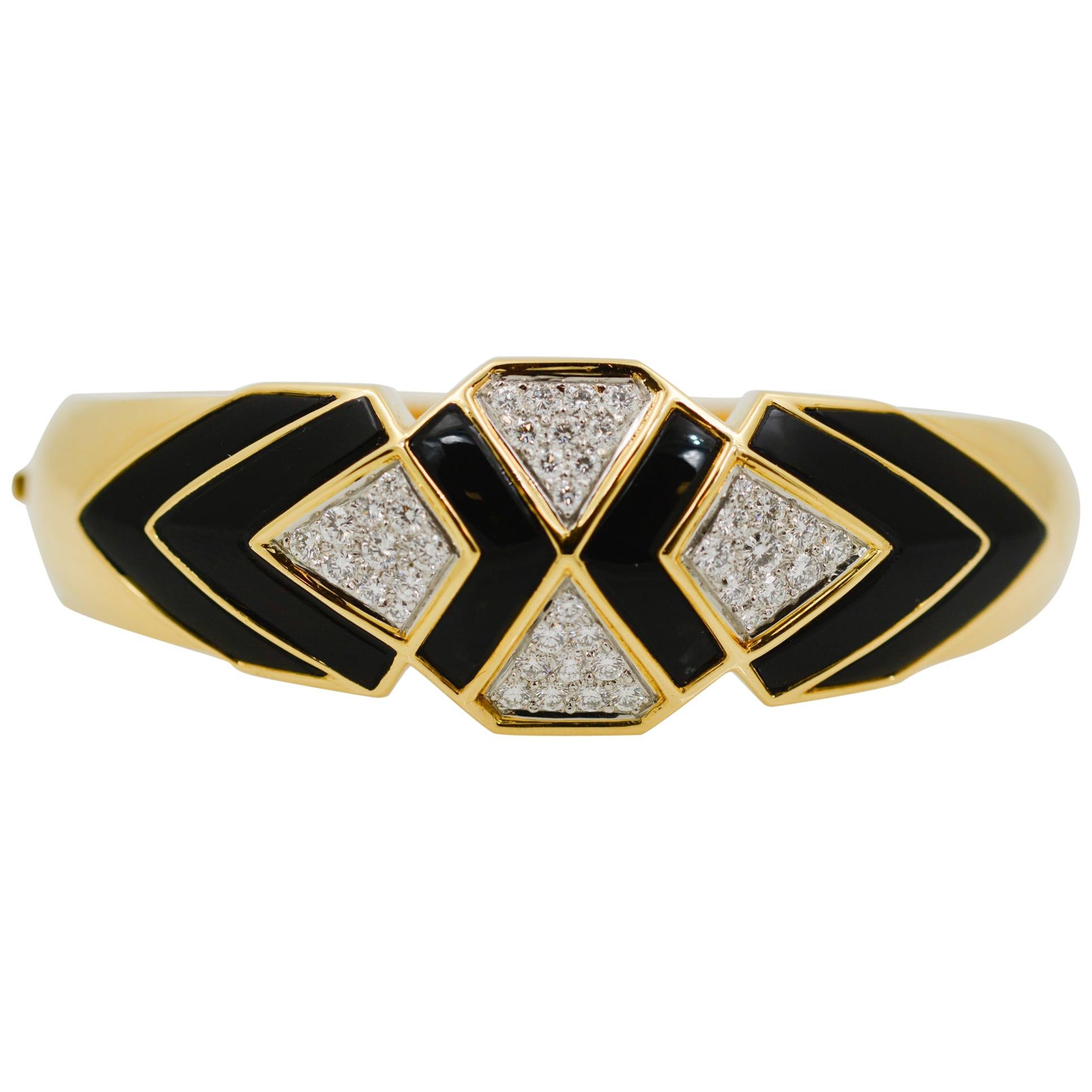 A bold black and white cuff crafted from 18 karat yellow gold featuring artfully cut geometric black onyx sections accenting angular sections of beautiful pave set diamonds. The stunning contrast of the black onyx against the white diamonds truly