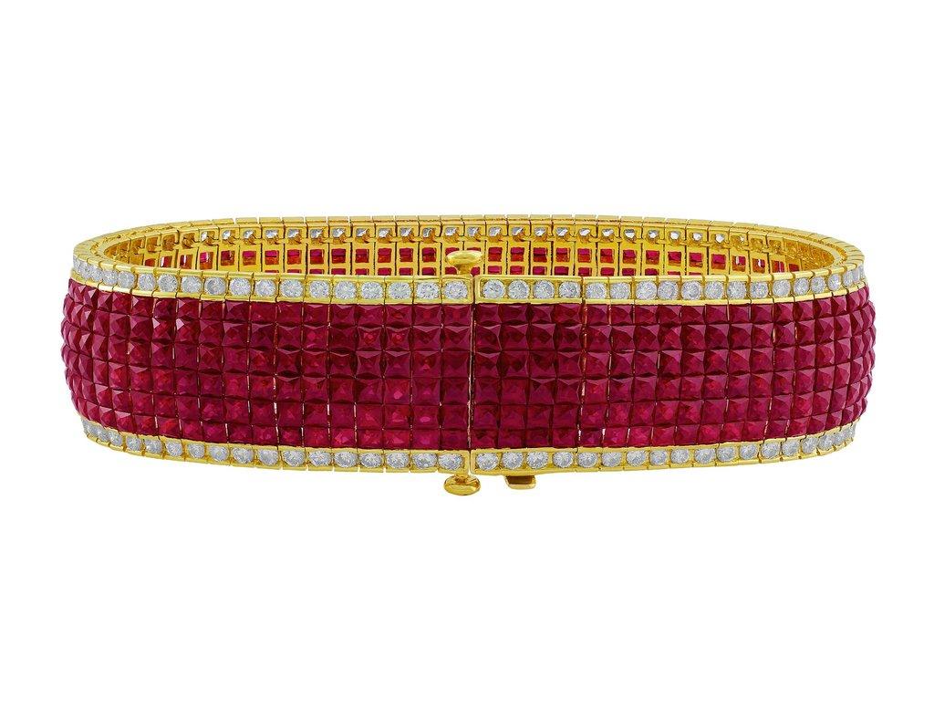 This magnificent bracelet has diamonds and synthetic rubies set in an invisible 18kt yellow gold setting, which showcases the beauty of the gleaming gemstones. The bracelet is fastened by an 18kt yellow gold box clasp.