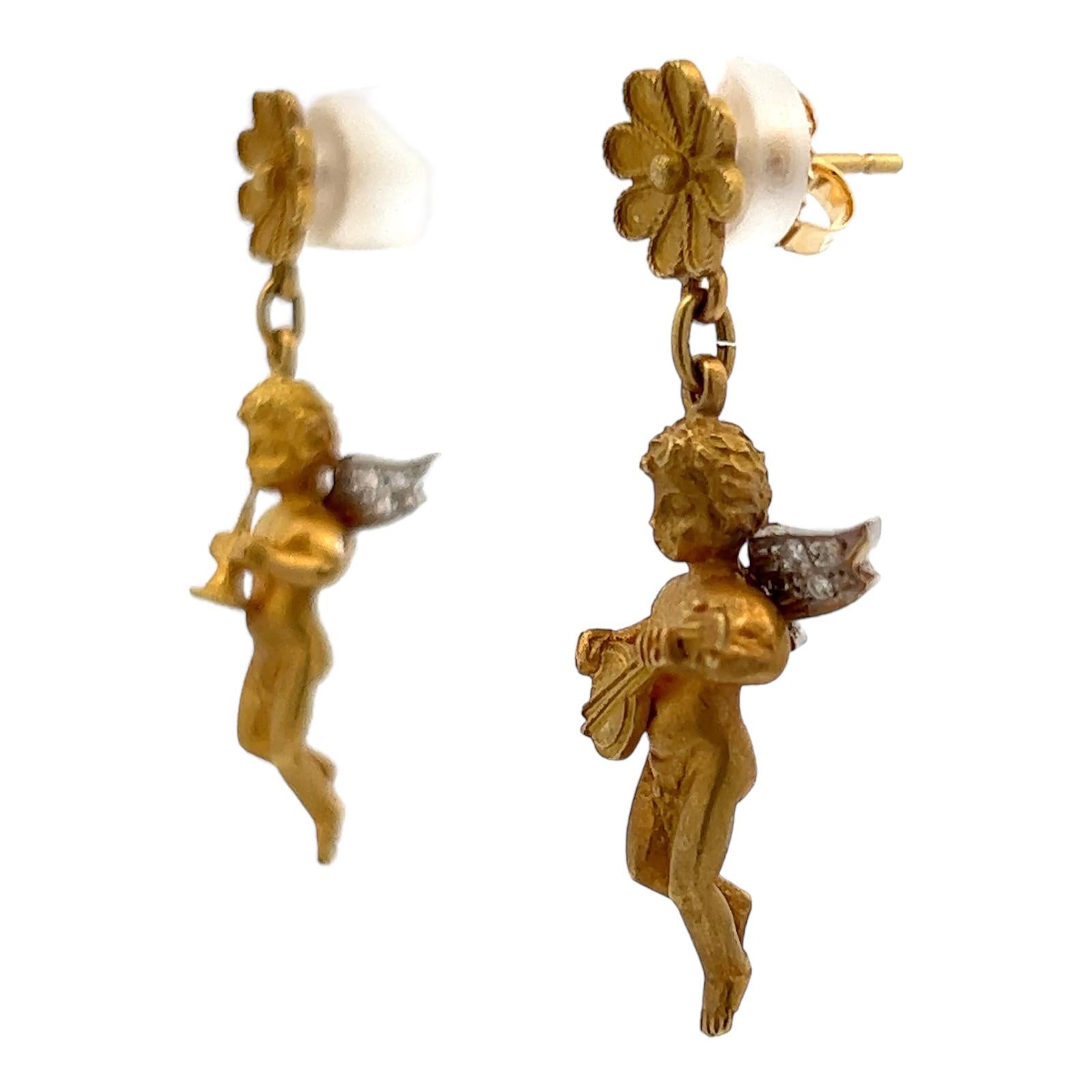 Unique and beautiful diamond drop earrings handcrafted in 18 karat yellow gold. The cherubs are playing instruments and their wings are accented with 12 round brilliant cut diamonds weighing approximately .12 CTW. The diamonds are graded G-H color