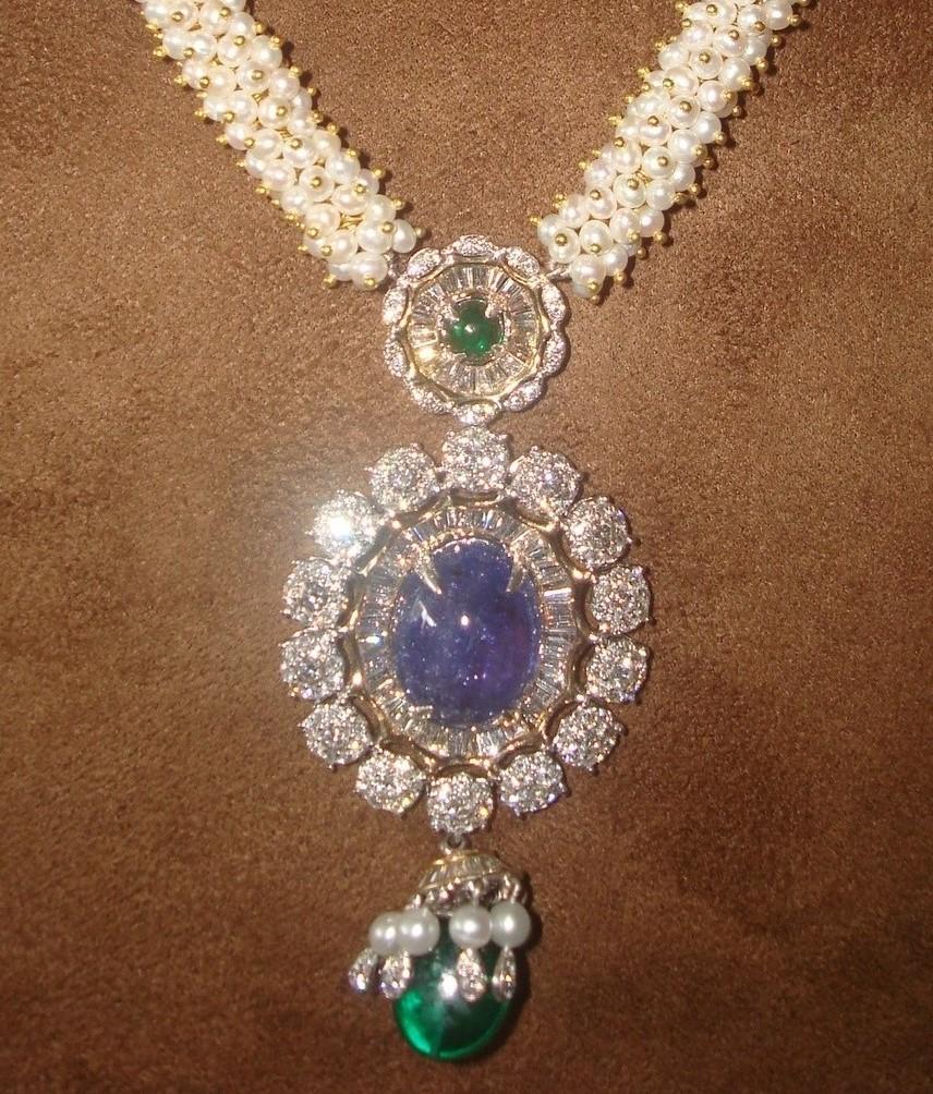 This satouir is an assembly of brilliant cut , baguettes along with a centre Tanzanite oval cabochon, Zambian Emeralds and culture pearls. Calibrated baguettes are set in a precise manner which resemble a sunburst. Brilliant cut diamonds are set in