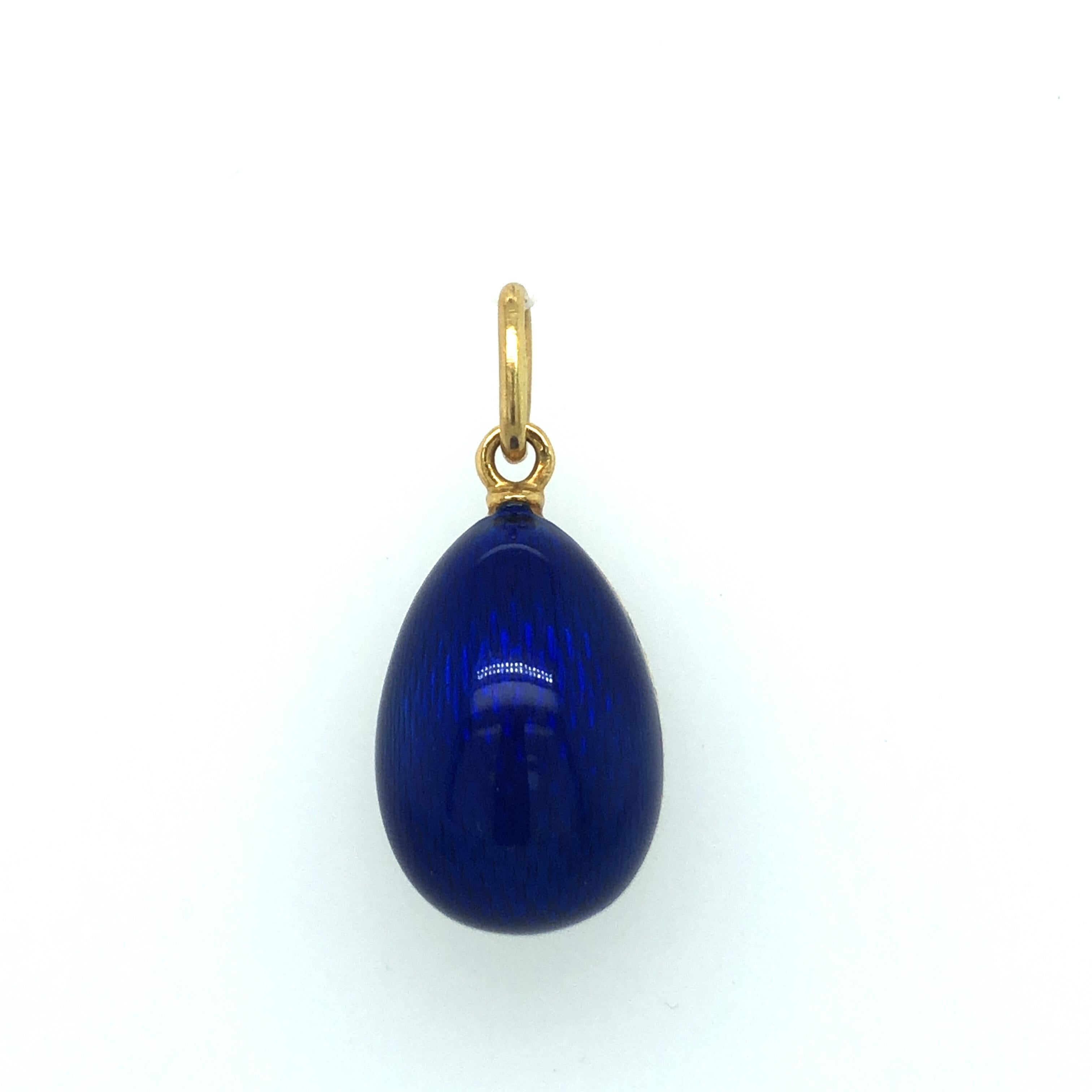 Delightful 18 karat yellow gold, diamond and guilloché blue enamel modern Fabergé egg charm/pendant.
The pendant is crafted in 18 karat yellow gold and covered by shimmering guilloché blue enamel. The front side features 3 flame-shaped yellow gold