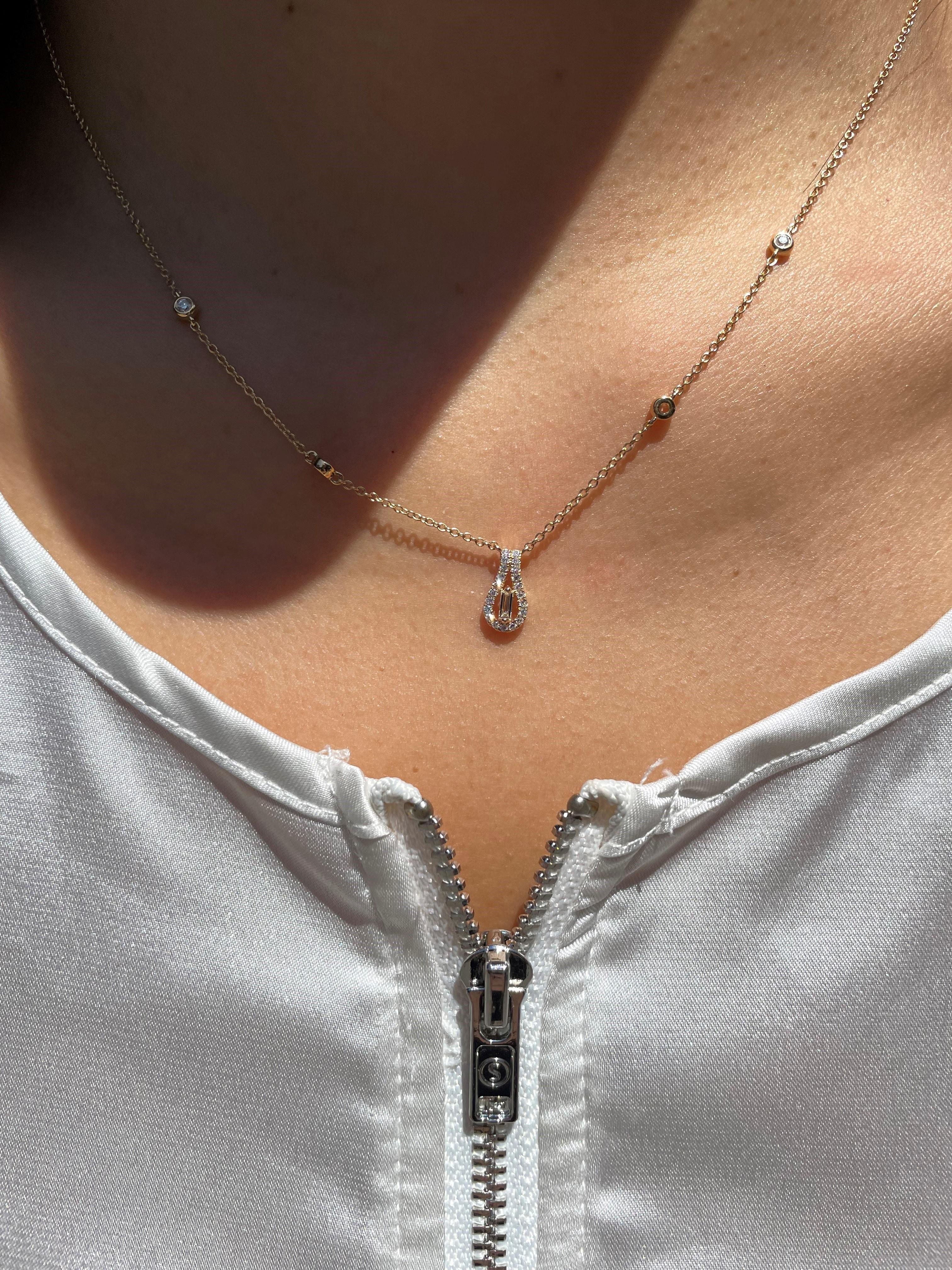 This elegant necklace is crafted of 18 karat yellow gold with a loop formed pendant. Features include diamonds stationed throughout the chain and on the pendant. Total carat weight of diamonds is 0.26 carats. Chain length is 18