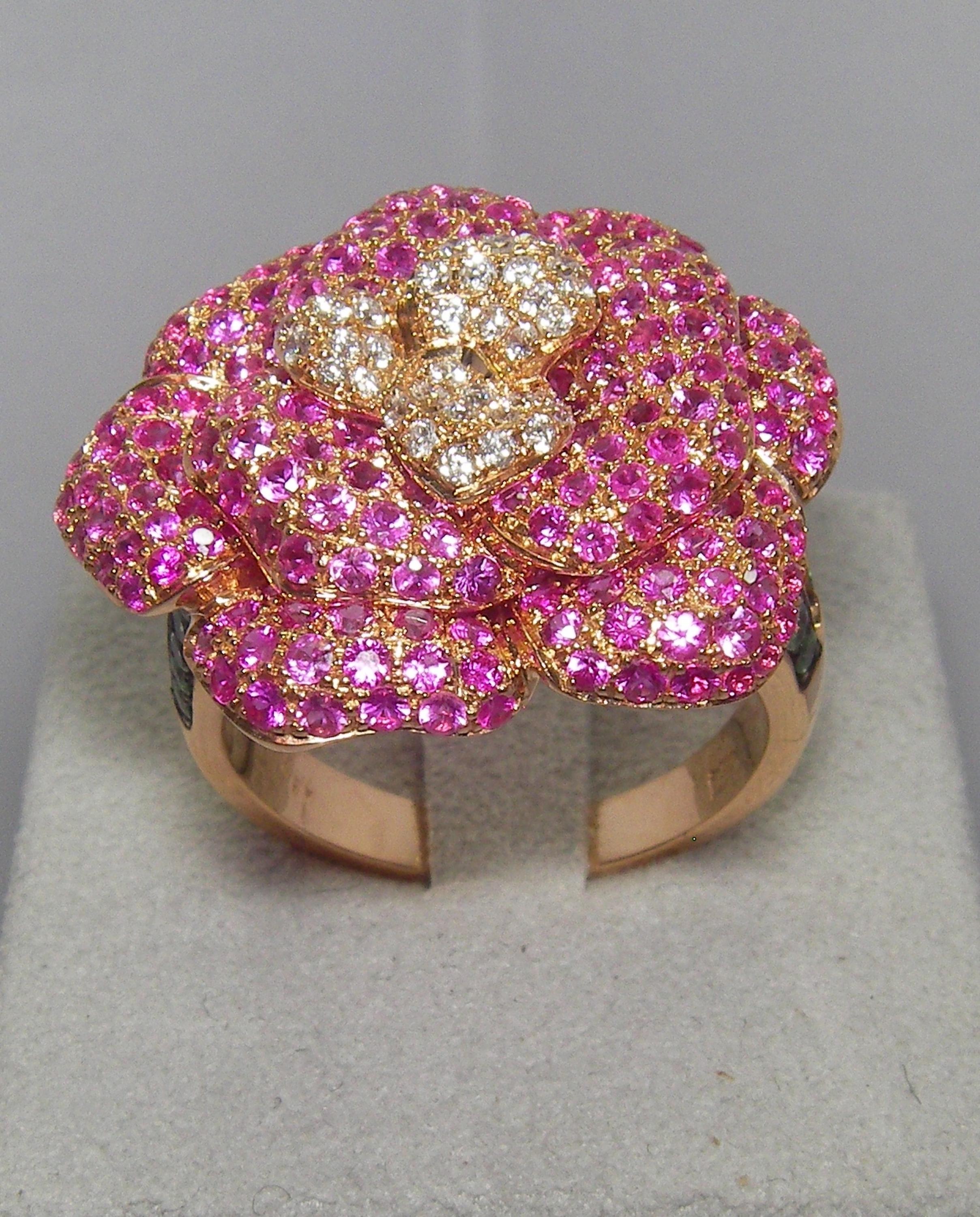 Delicate flower shaped 18 Karat Yellow Gold Cocktail ring. Embellished with Pink Sapphire petals and a Diamond center accented with vivid green Tsavorite. A indisputably beautiful crafted piece and a perfect compliment to our Yellow Gold Diamond and