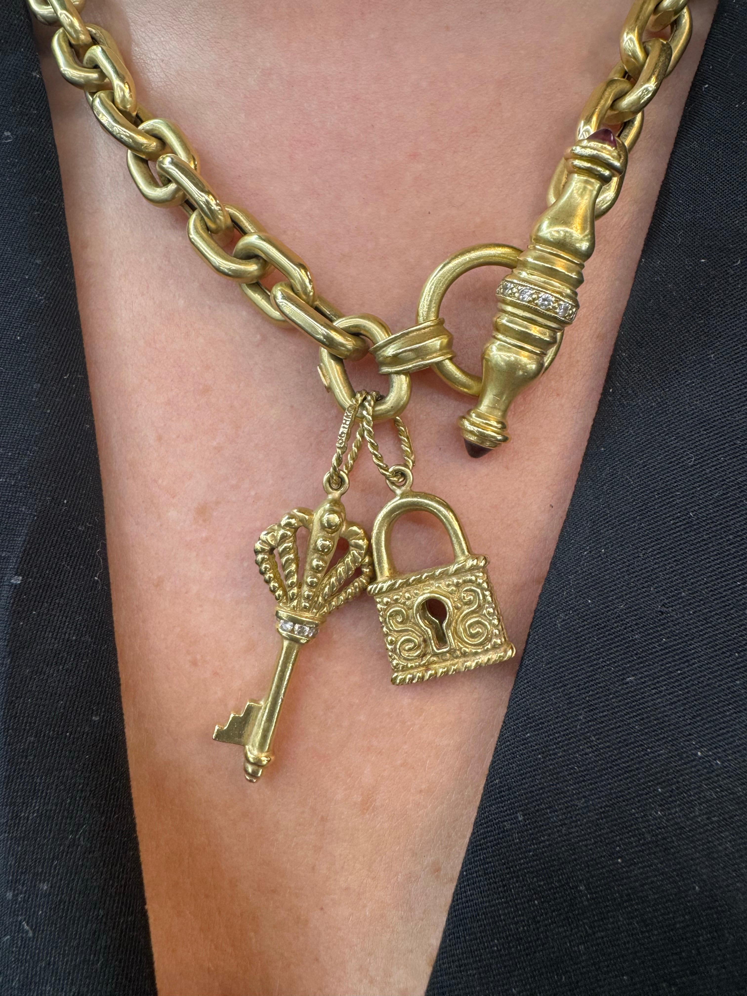 Bold and whimsical, this statement toggle necklace is crafted in rich 18 karat yellow gold and weighs a substantial 32.4 grams. The chunky chain features an elegant toggle clasp adorned with three intricately detailed charms: an ornate key, a