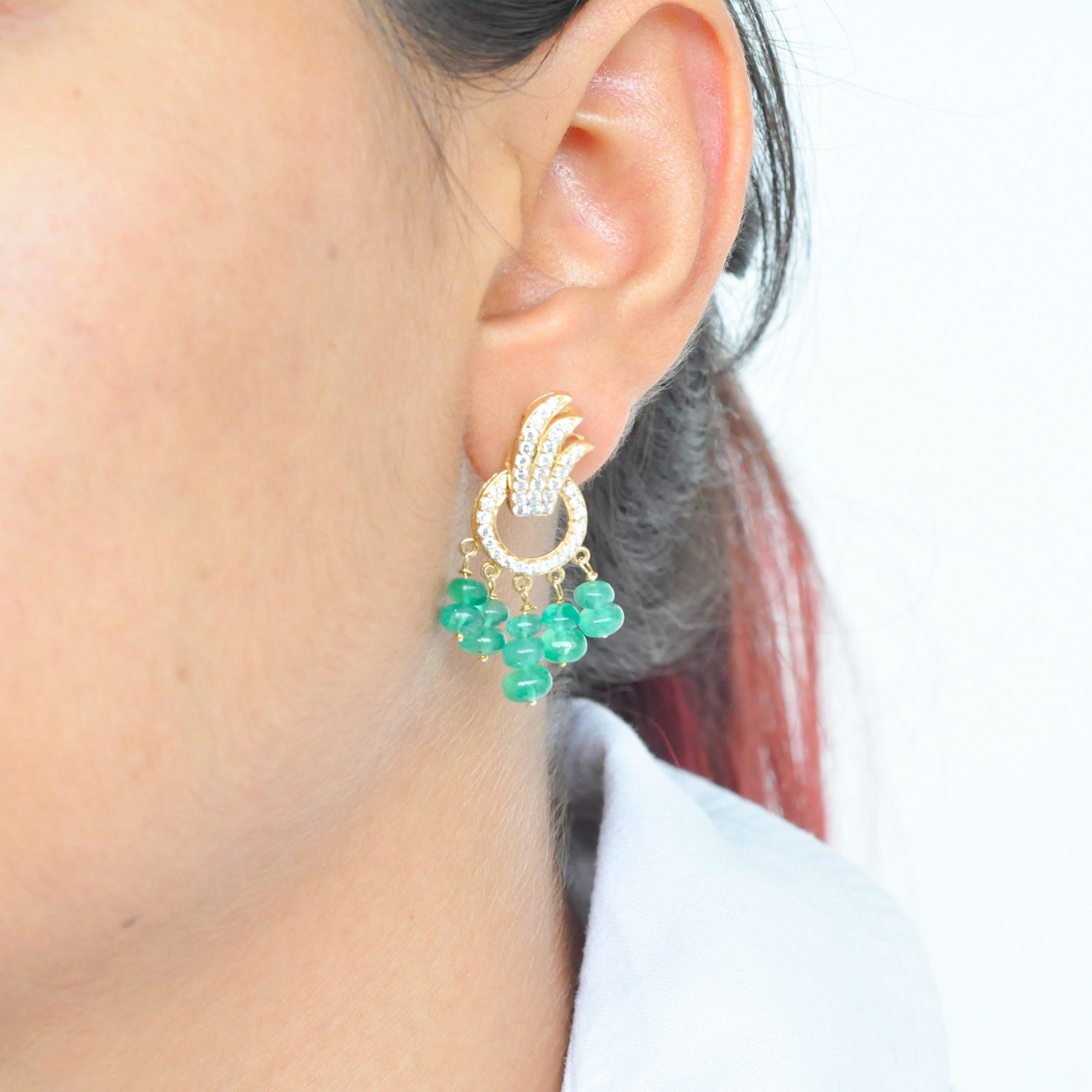 18 karat yellow gold diamond emerald beads dangle earrings

These 18 karat gold dangle earrings are a contemporary beauty. The earrings depicts three diamond feathers encircled by a diamond ring. A touch of green added by the hanging lustrous