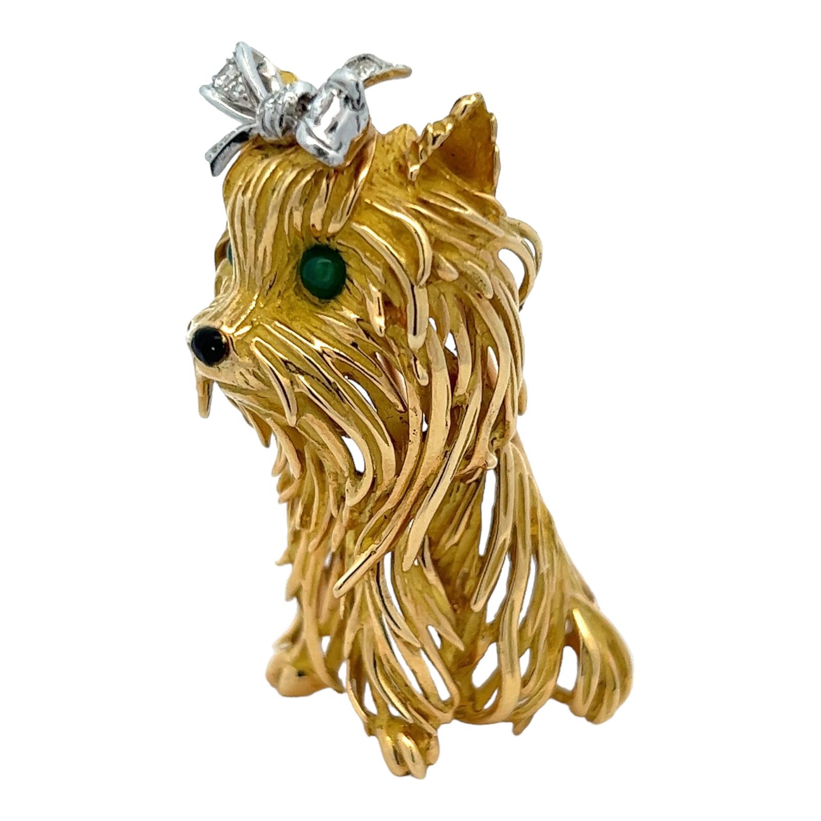 Adorable handcrafted dog pin fashioned in 18 karat yellow gold. The dog brooch features a diamond bow with 16 diamonds weighing approximately .17 CTW, and emerald eyes. The dog measures 1.75 inches in length and 20mm in width. Great gift idea for