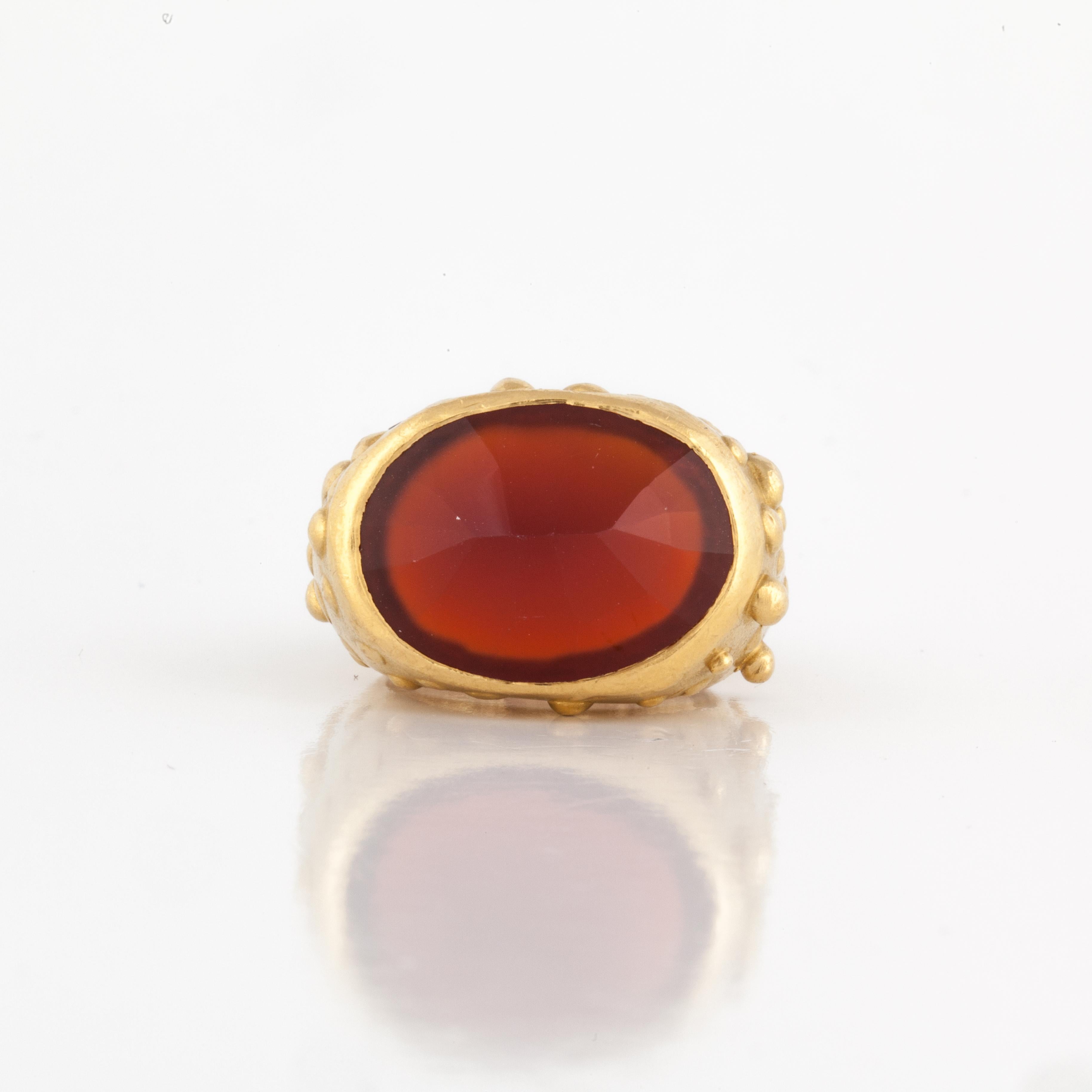 Modernistic 18K yellow gold ring featuring a faceted carnelian.  In addition, there are four round diamonds with a total carat weight of .05; G-H color and SI1 clarity. Presentation area is 1 inch by 5/8 inches and sits 1/2 inch off the finger.