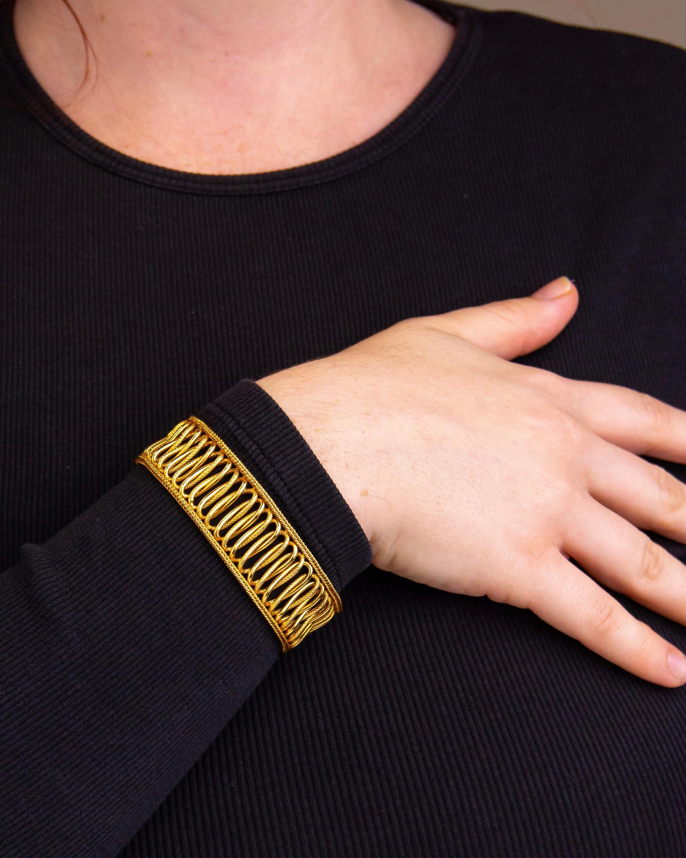 Questo bracciale vintage è stato realizzato in oro giallo 18 carati e probabilmente è stato prodotto negli ultimi 50 anni. Il bracciale a maglie fantasia presenta motivi a forma di otto che si alternano tra oro lucido e oro strutturato. I due bordi