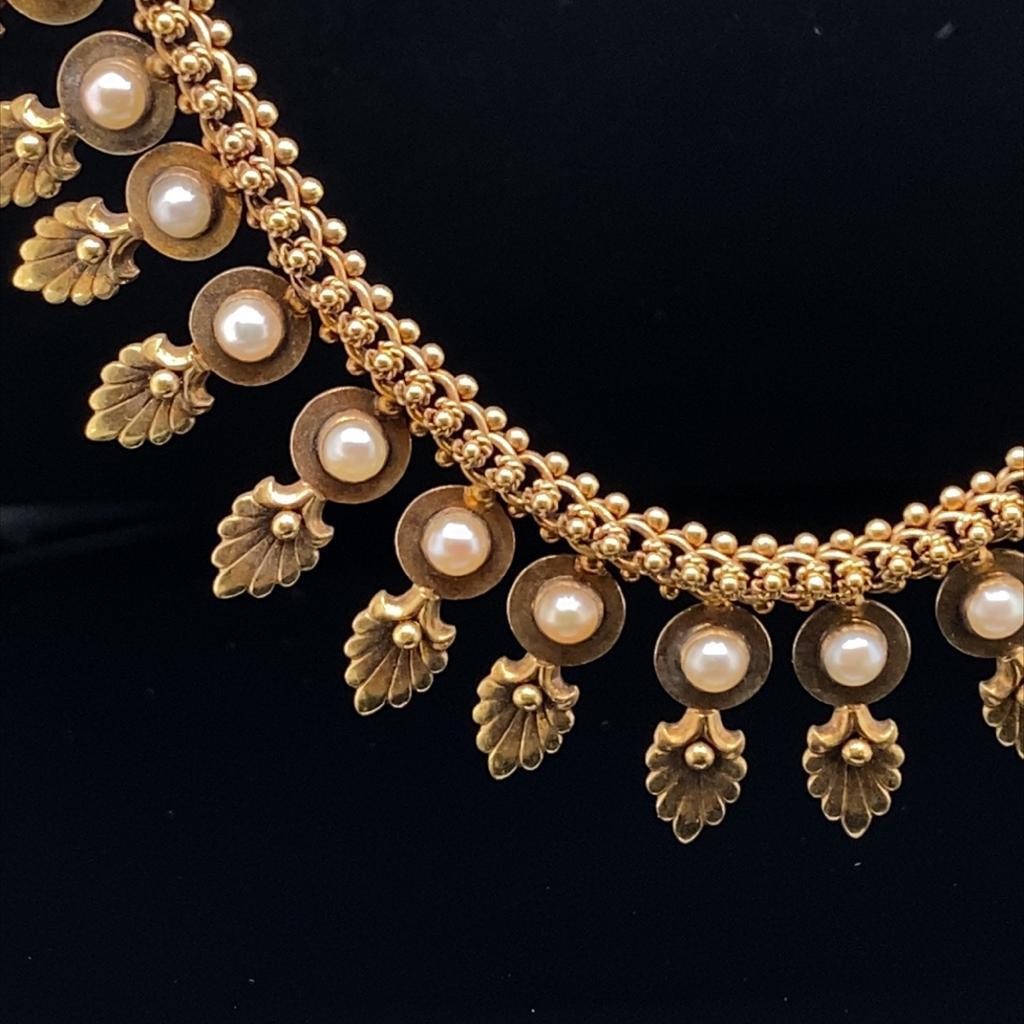 A striking vintage gold fringe collar set with pearls in 18ct yellow gold, circa 1960.

This exceptionally finely crafted piece features an articulated thick belcher chain running along the length of the necklace from which a series of individual
