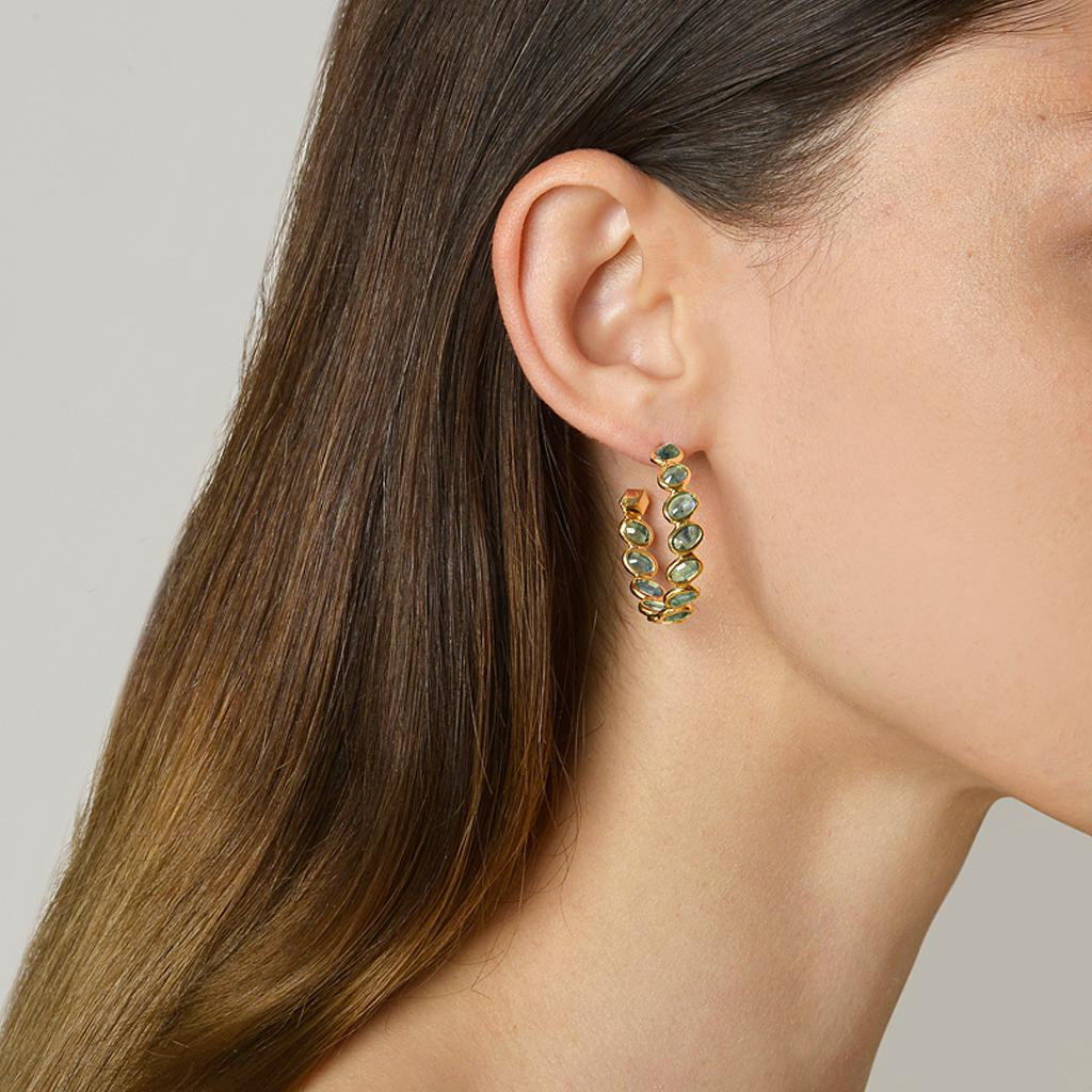 18kt yellow gold Ombré hoop earrings with bezel set multishade oval green sapphires at 11 o'clock® and signature Brillante® motif, medium.

Reimagined from summers spent at the Tuscan shore, the Ombré collection highlights the diverse hues and