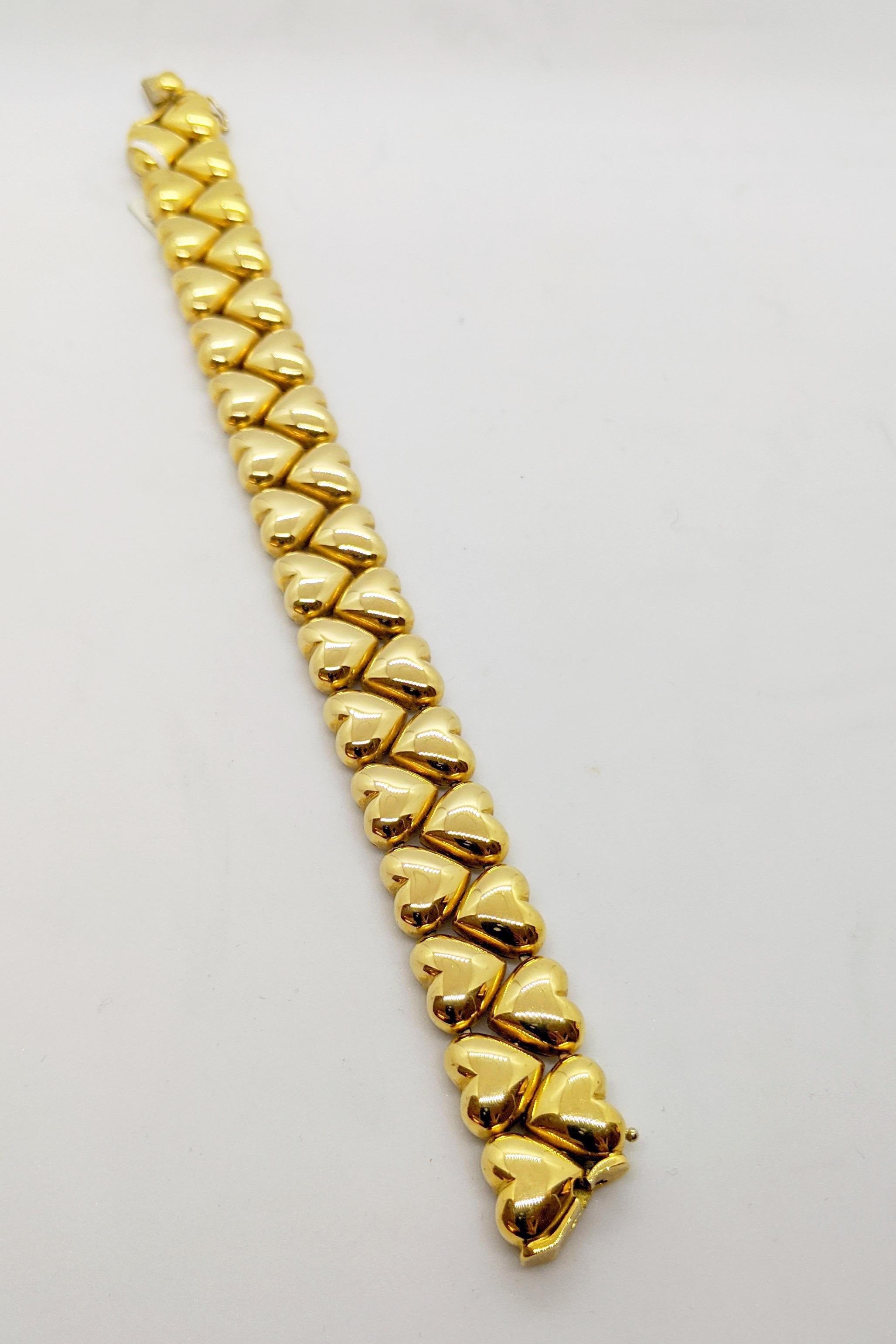 This is an 18 karat yellow gold flexible heart link bracelet. The bracelet is designed with 32 high polished yellow gold hearts set in a two row up and down pattern. It has a plunger type clasp and a figure 8 safety lock. The bracelet measures 7