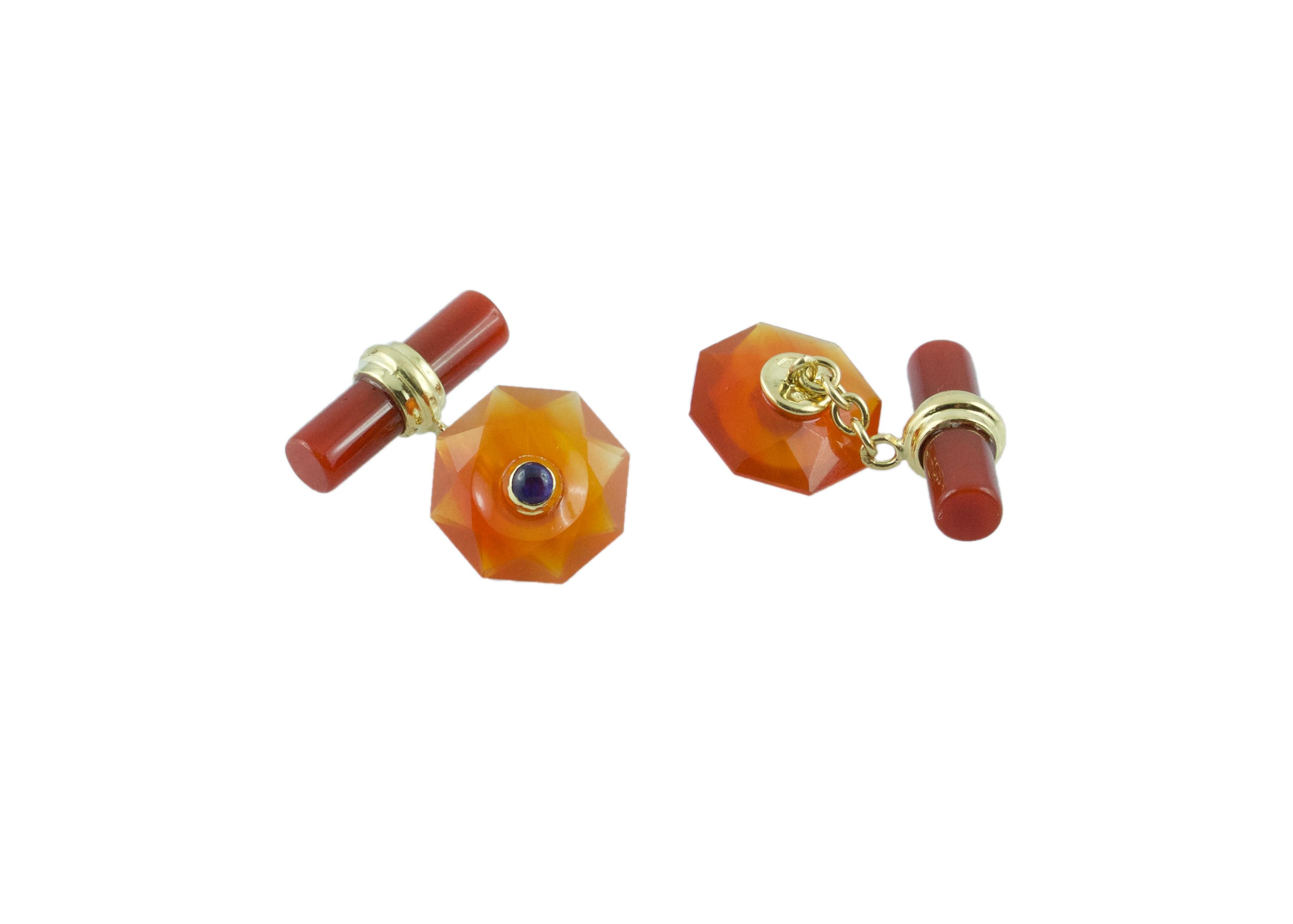 The front face of these exquisite cufflinks has a striking octagonal shape that is convex, multifaceted, and adorned in the center with a cabochon sapphire. Both the front face and the cylindrical toggle are in carnelian, with a post made of 18k