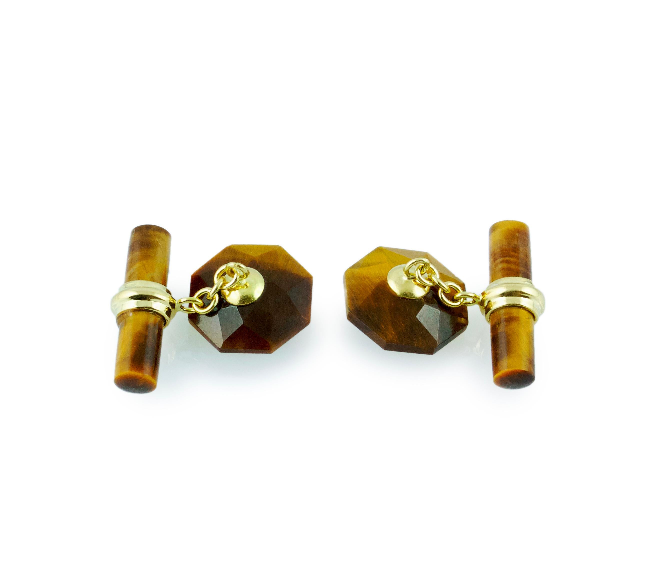 The front face of these exquisite cufflinks has a striking octagonal shape that is convex, multifaceted, and adorned in the center with a cabochon rubies. Both the front face and the cylindrical toggle are in Tiger's Eye, with a post made of 18k