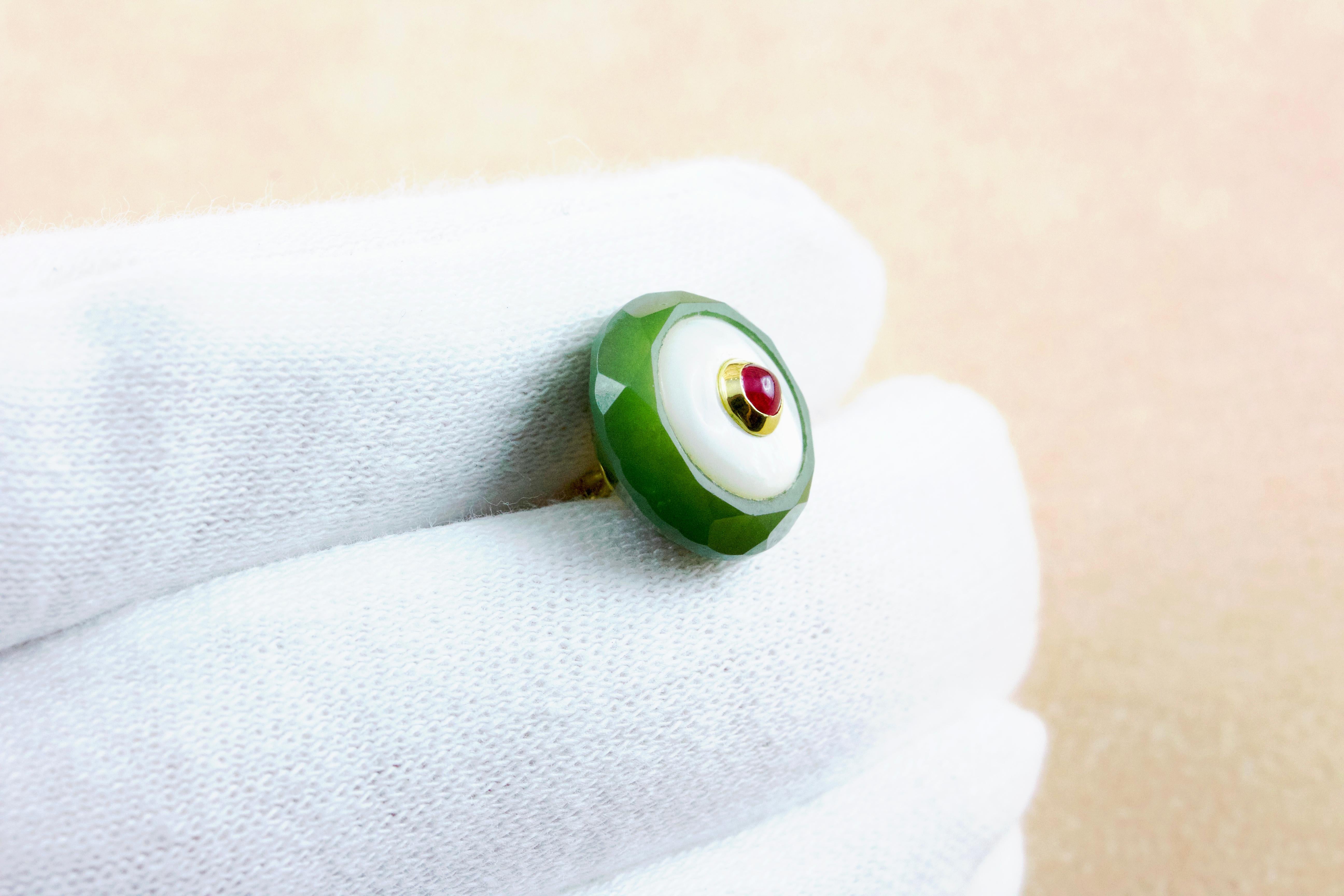 These exquisite cufflinks feature a round shape for front face and a delicate color palette, thanks to the warm green of the jade and the iridescent transparency of the mother of pearl. 
The center of each element is adorned with a cabochon ruby