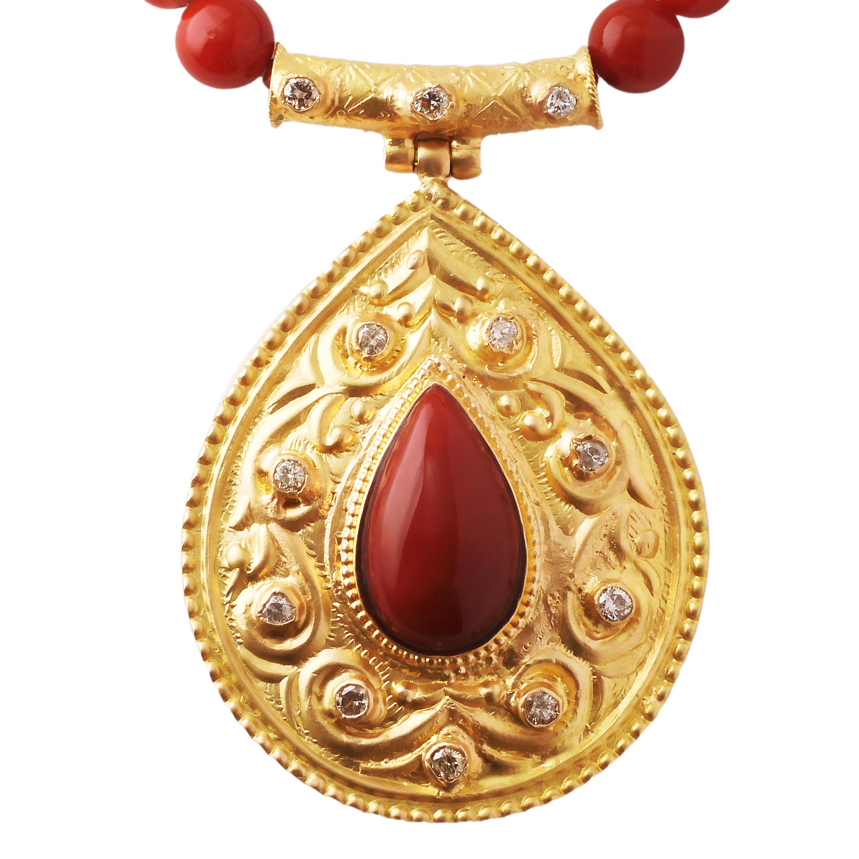 This is an 18 karat yellow gold pendant with a large pear shape Chiaka Sango (oxblood Coral) in the center. The 18 karat yellow gold pendant frame is engraved with an arabesque pattern with diamonds placed around the center.
The necklace is made of