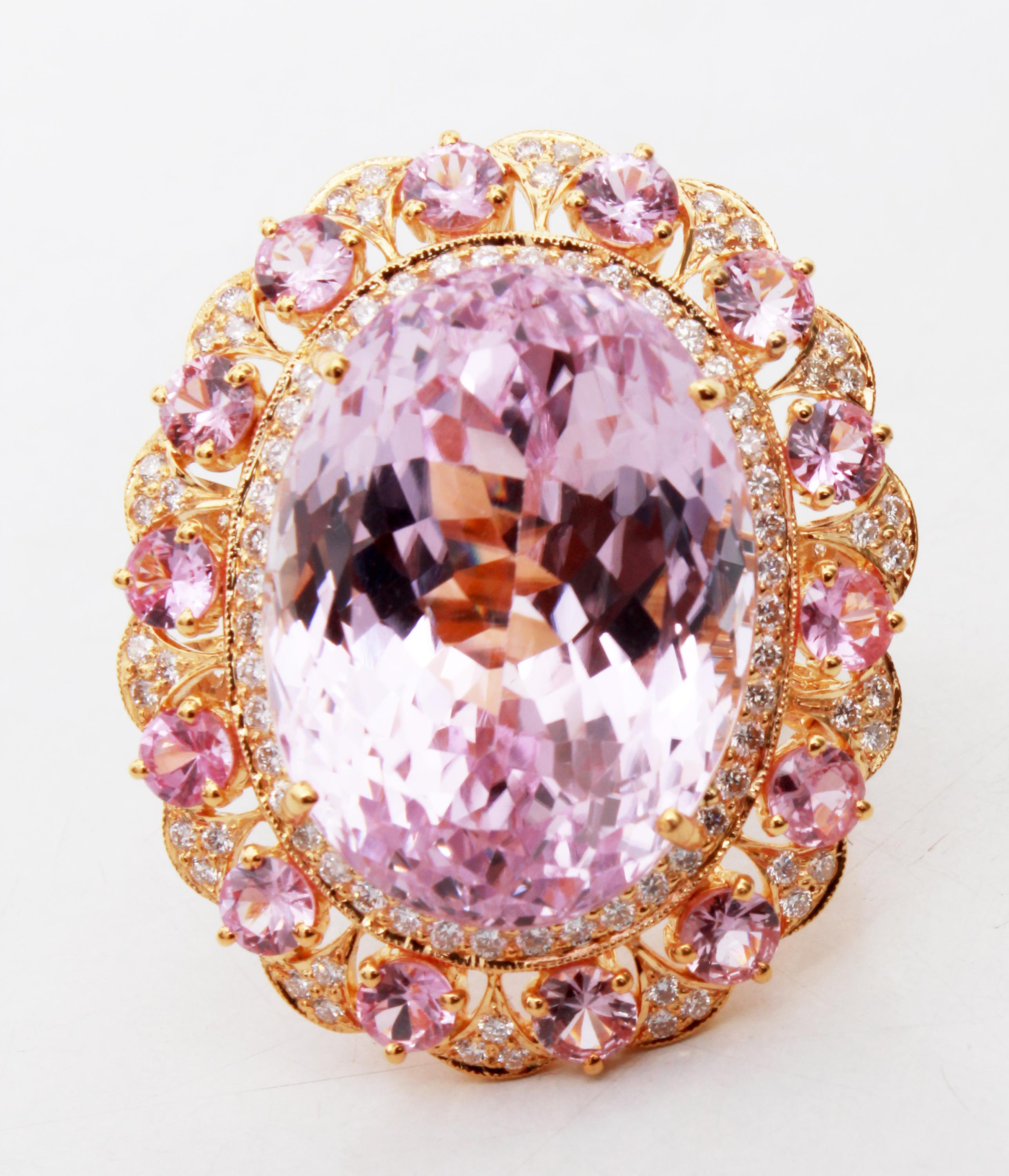 This beautiful ring has a huge 42.27 carat Kunzite that is set in the center of the ring and has 14 Round Pink Sapphires that weigh 3.04 carats. This ring also has 110 Round Cut Diamonds that weigh 1.32 carats and are set along the shank of the