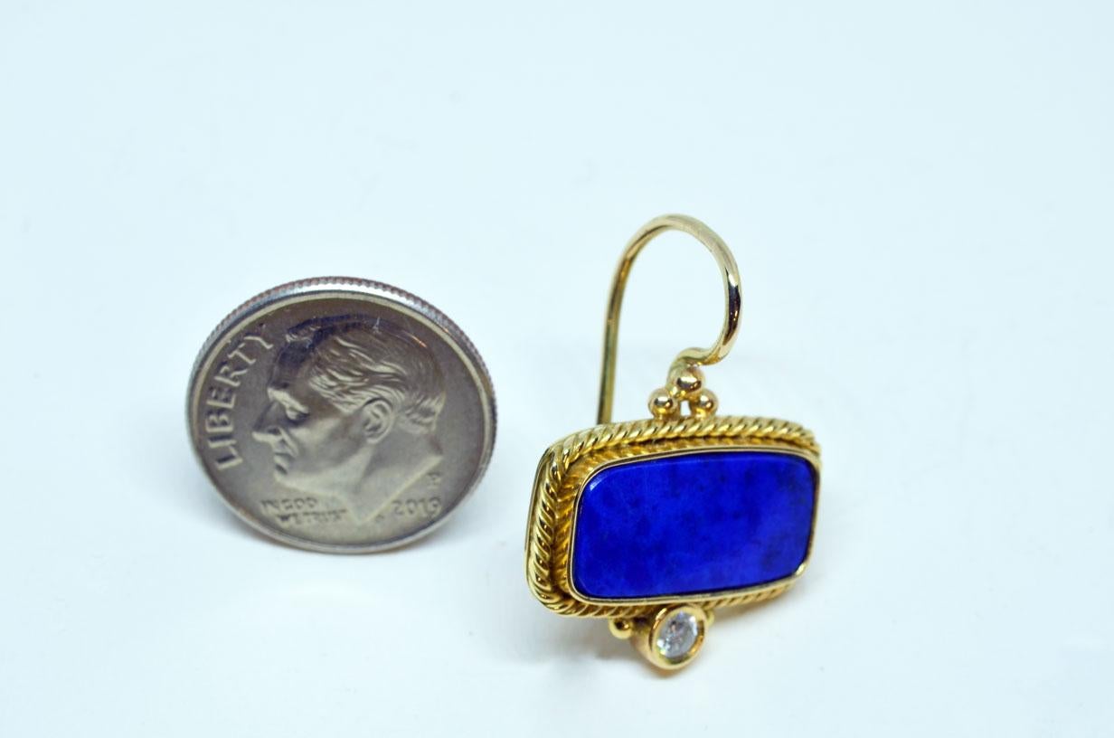 Lapis Lazuli and Diamond Earrings beautifully handcrafted in 18 Karat Yellow Gold. 18X8.5mm cushioned rectangle fine Lapis Lazuli, bezel set with a three strand rope border, accented with two bezel set round brilliant Diamonds. Each diamond weighs