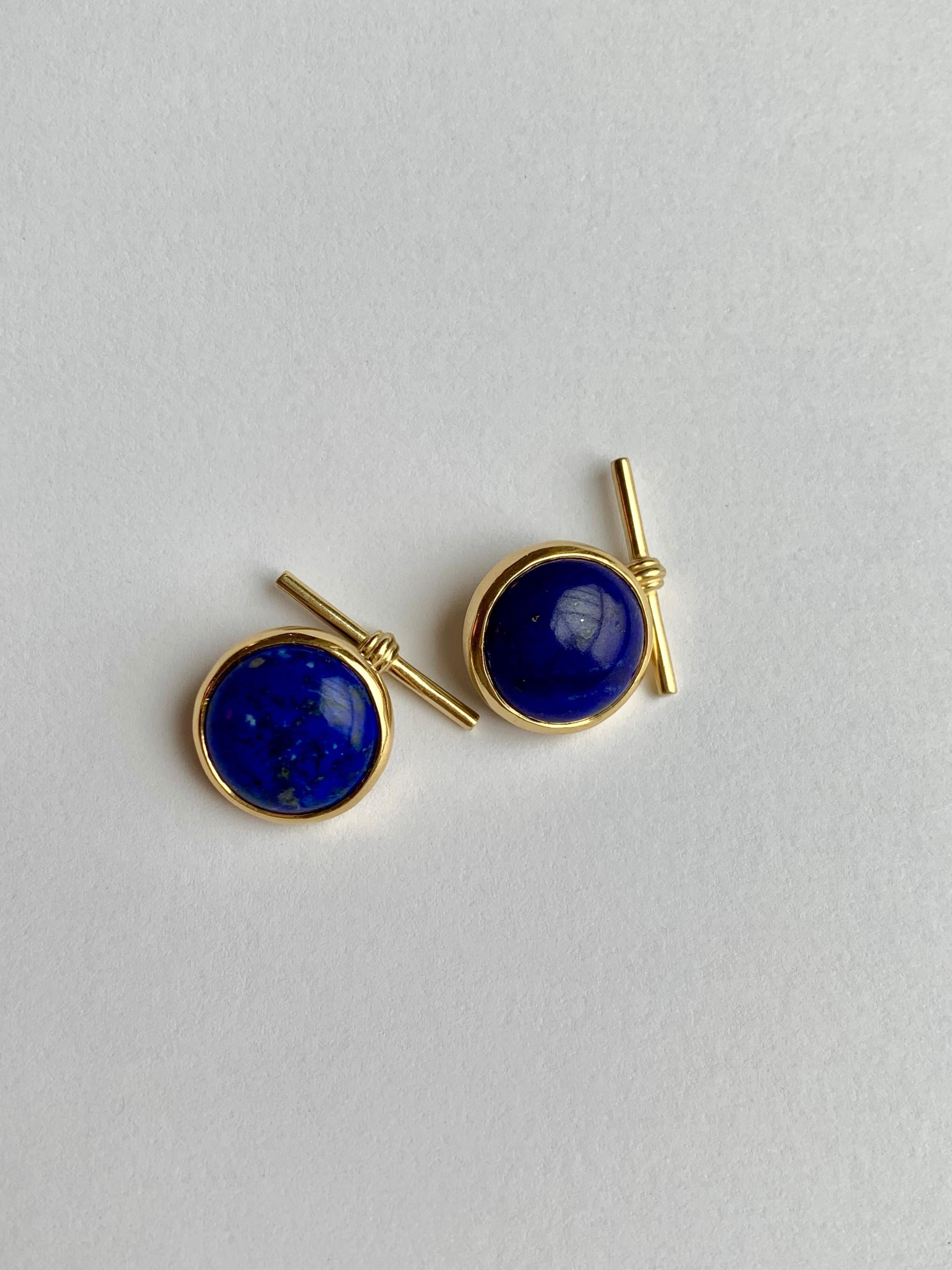 The striking blue shade of Lapis Lazuli with natural inclusions is set off nicely with yellow gold mounting. These round cabochon cut cufflinks set in 18 karat yellow gold with chain and gold T bar are modern and sophisticated. 

- 18 karat yellow