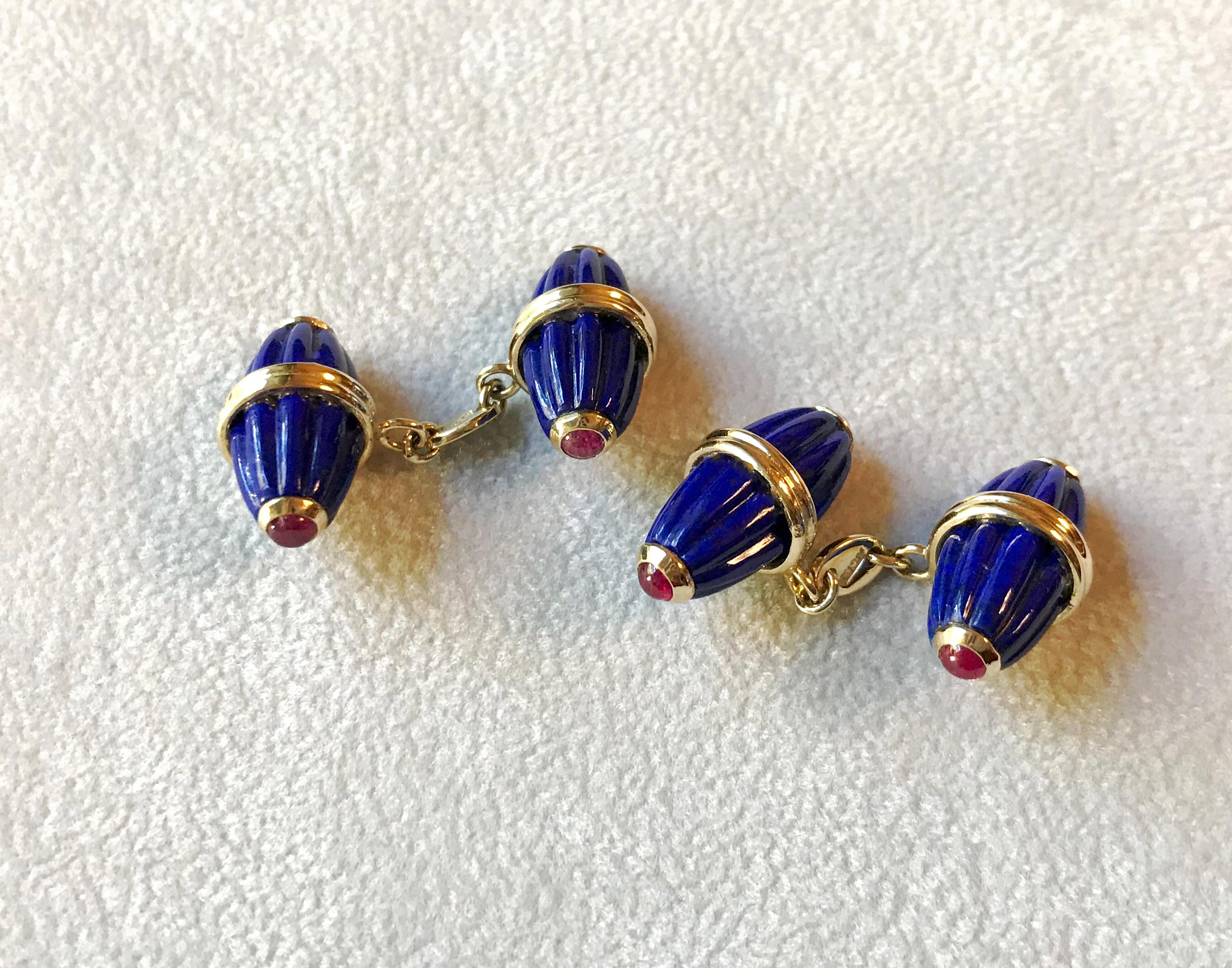 These striking cufflinks feature identical front face and toggle whose oval shapes evokes the silhouette of a barrel, carved with grooves that add dynamism to their texture. They are made of lapis lazuli, adorned with cabochon rubies at the edges.