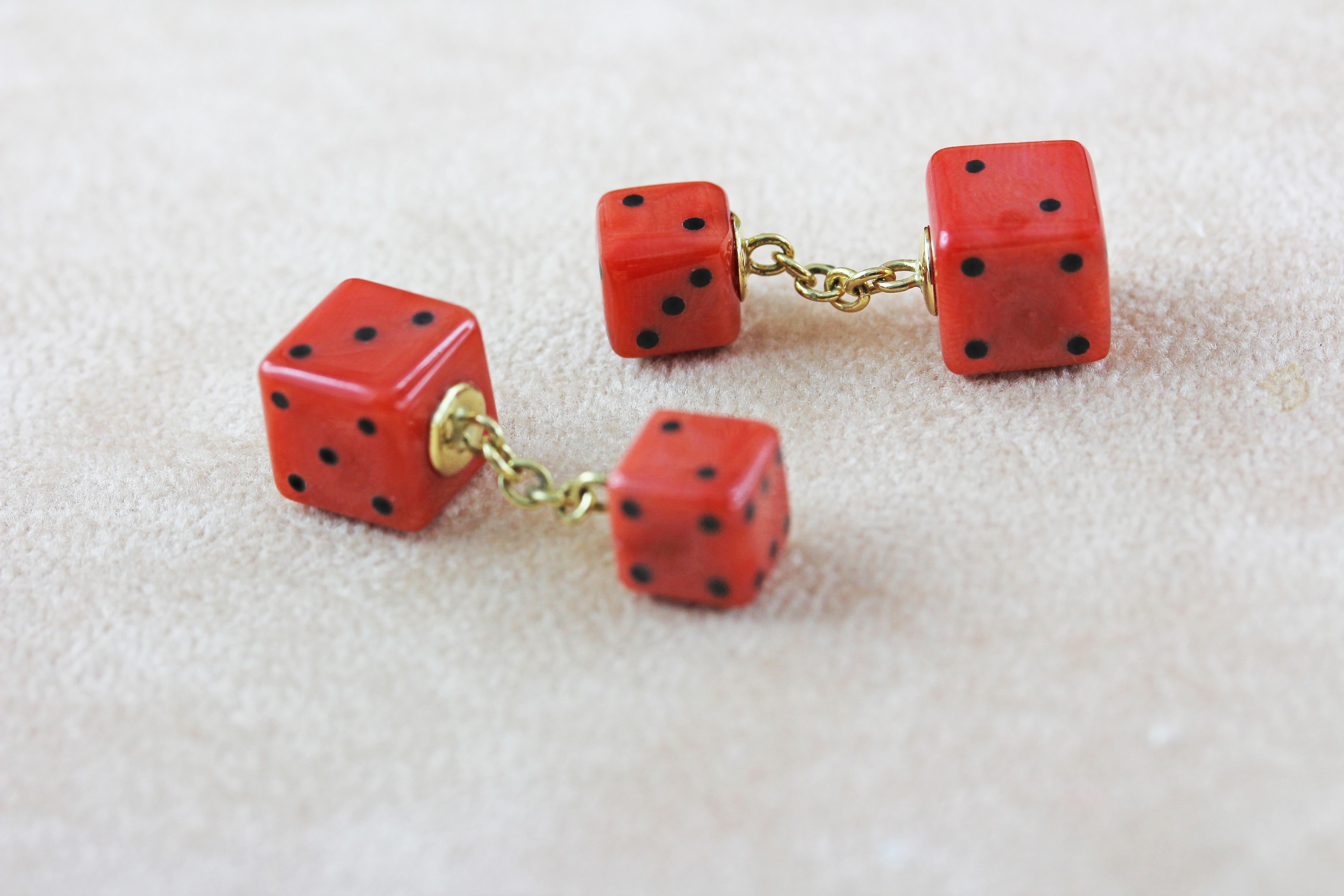This sophisticated pair of cufflinks is entirely made of Mediterranean coral , the front face is shaped as a playing dice with its striking red surface highlighted by black onyx to recreate the faces of a dice , 
the toggle is a smaller dice and is 