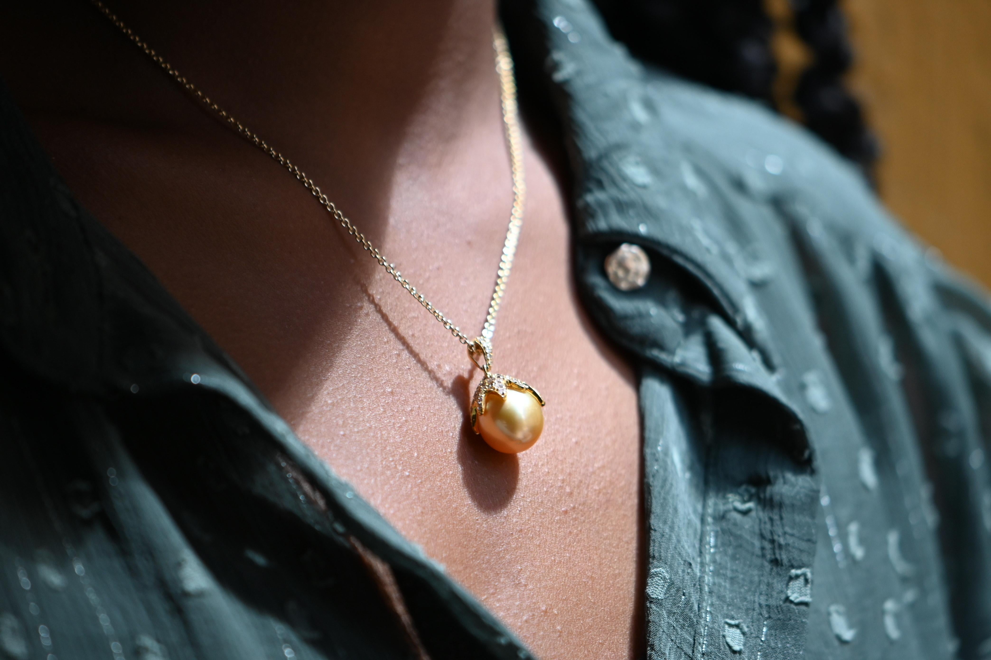 This exquisite necklace is crafted in 18 karat yellow gold and showcases a magnificent champagne-colored South Sea pearl, measuring approximately 12 to 14 mm in diameter. The pearl displays a warm, golden luster with subtle iridescence — a hallmark