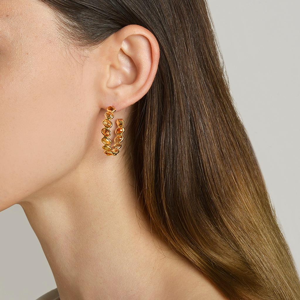 18kt yellow gold Ombré hoop earrings with bezel set multishade oval orange sapphires at 11 o'clock® and signature Brillante® motif, medium. 

Reimagined from summers spent at the Tuscan shore, the Ombré collection highlights the diverse hues and