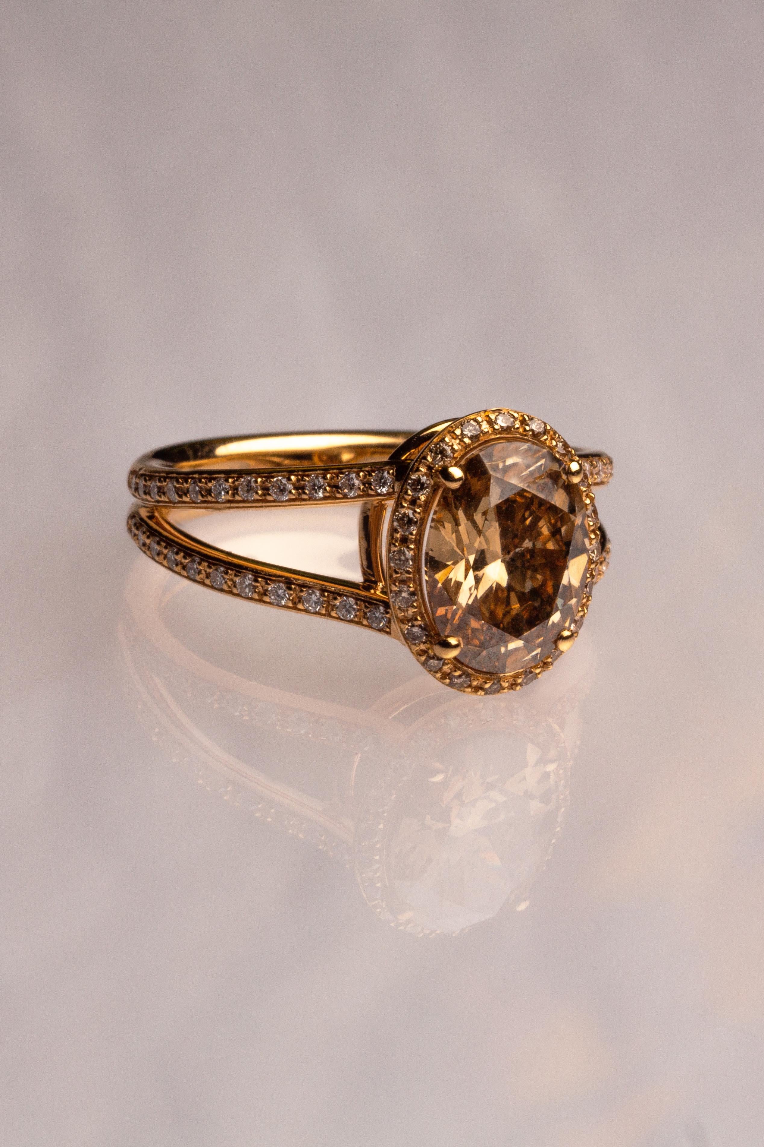 This 18K yellow gold stunning solitaire ring is from our Divine Collection. The centre stone is oval shape brown diamond in total of 2.07 Carat which is decorate by round colorless diamonds in total of 0.20 Carat and round brown diamonds in total of