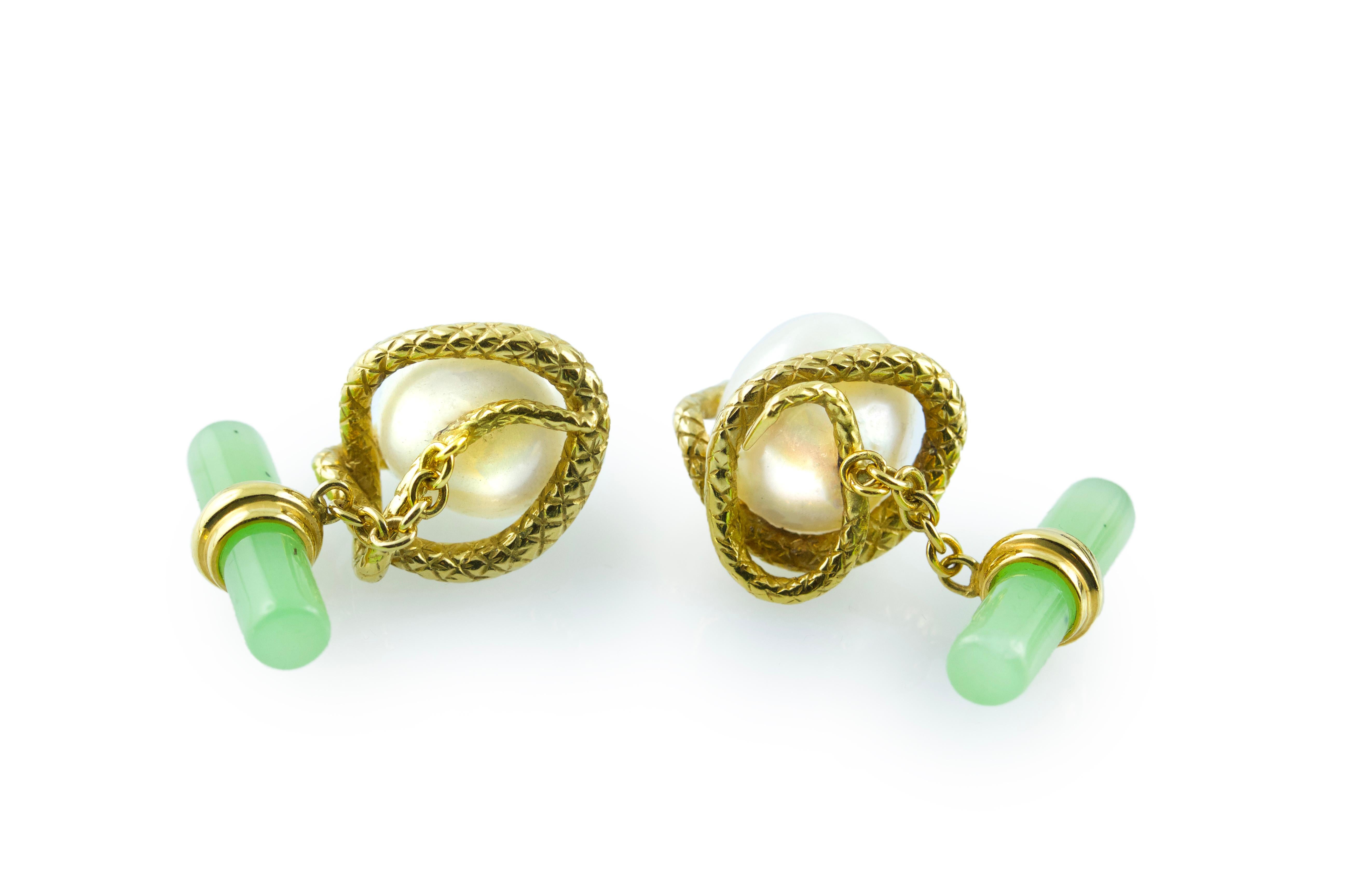 This magnificent pair of cufflinks features a baroque pearl gracing the front face, mounted on an 18 karat yellow gold piece shaped as a snake coiled all around the pearl. 
In gold is also the post that wraps around the cylindrical shape of the
