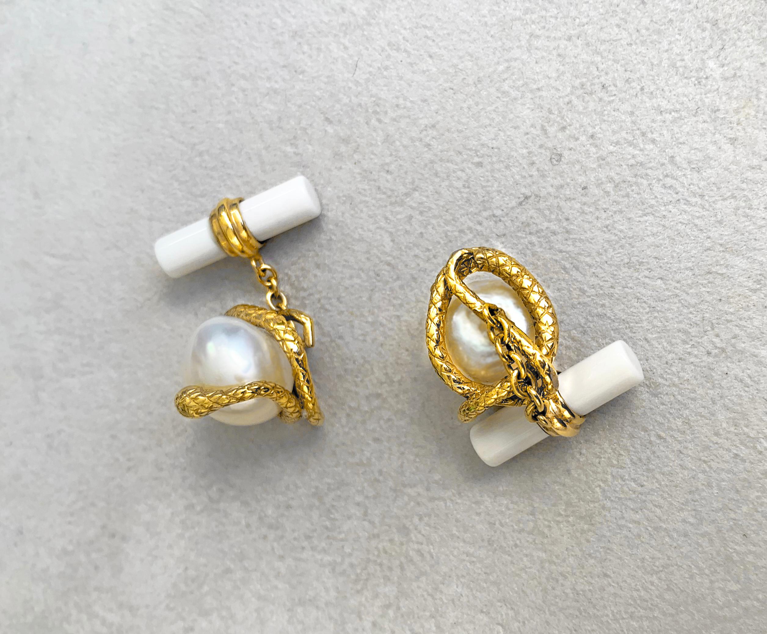 This magnificent pair of cufflinks features a baroque pearl gracing the front face, mounted on an 18k yellow gold piece shaped as a snake coiled all around the pearl. In gold is also the post that wraps around the cylindrical shape of the toggle,