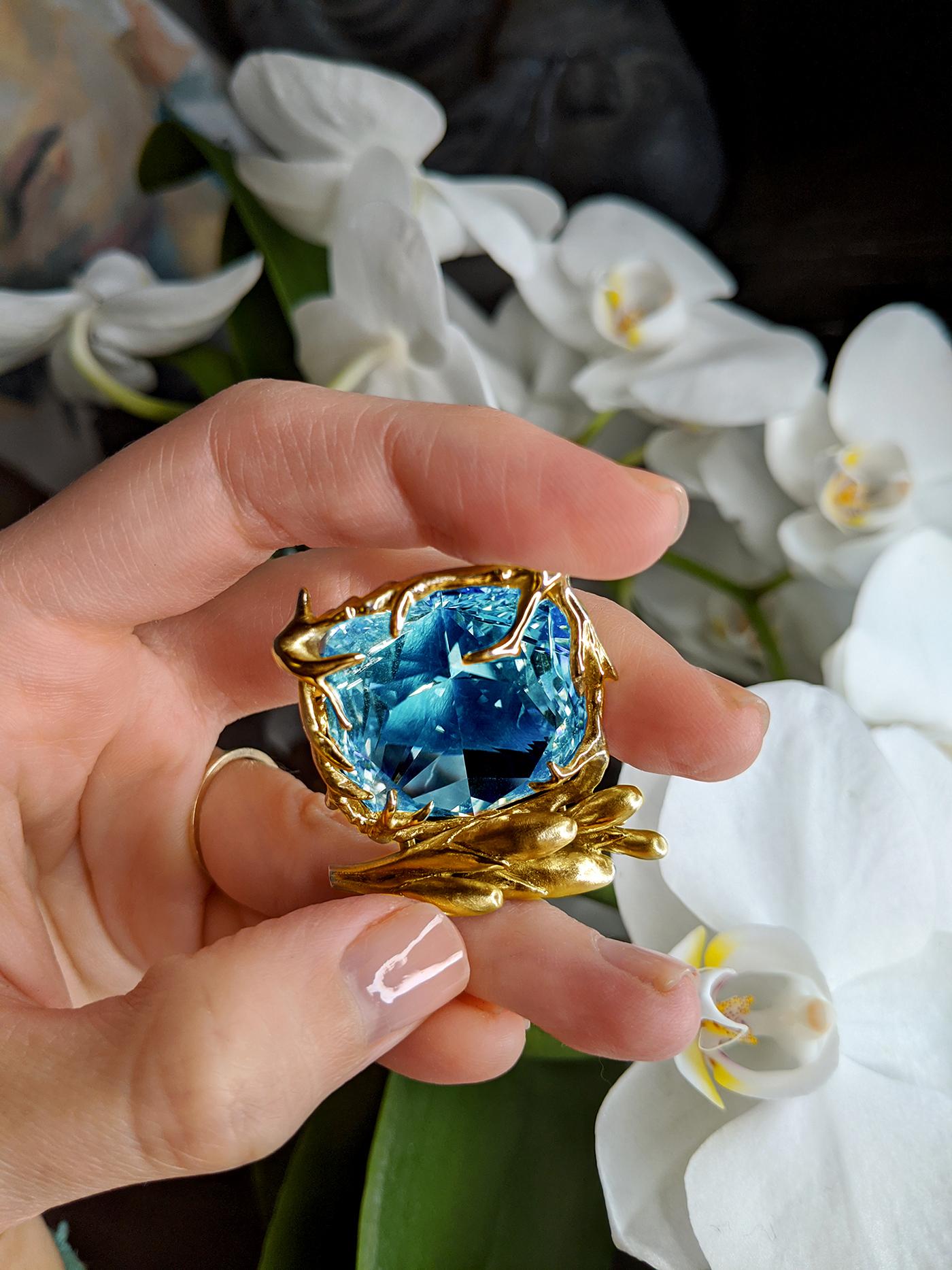 This pendant necklace features a large blue topaz at its center, set in 18 karat yellow gold. The size of the topaz makes its vivid marine color even more striking, and it complements the bright and saturated gold perfectly.

The artist behind this