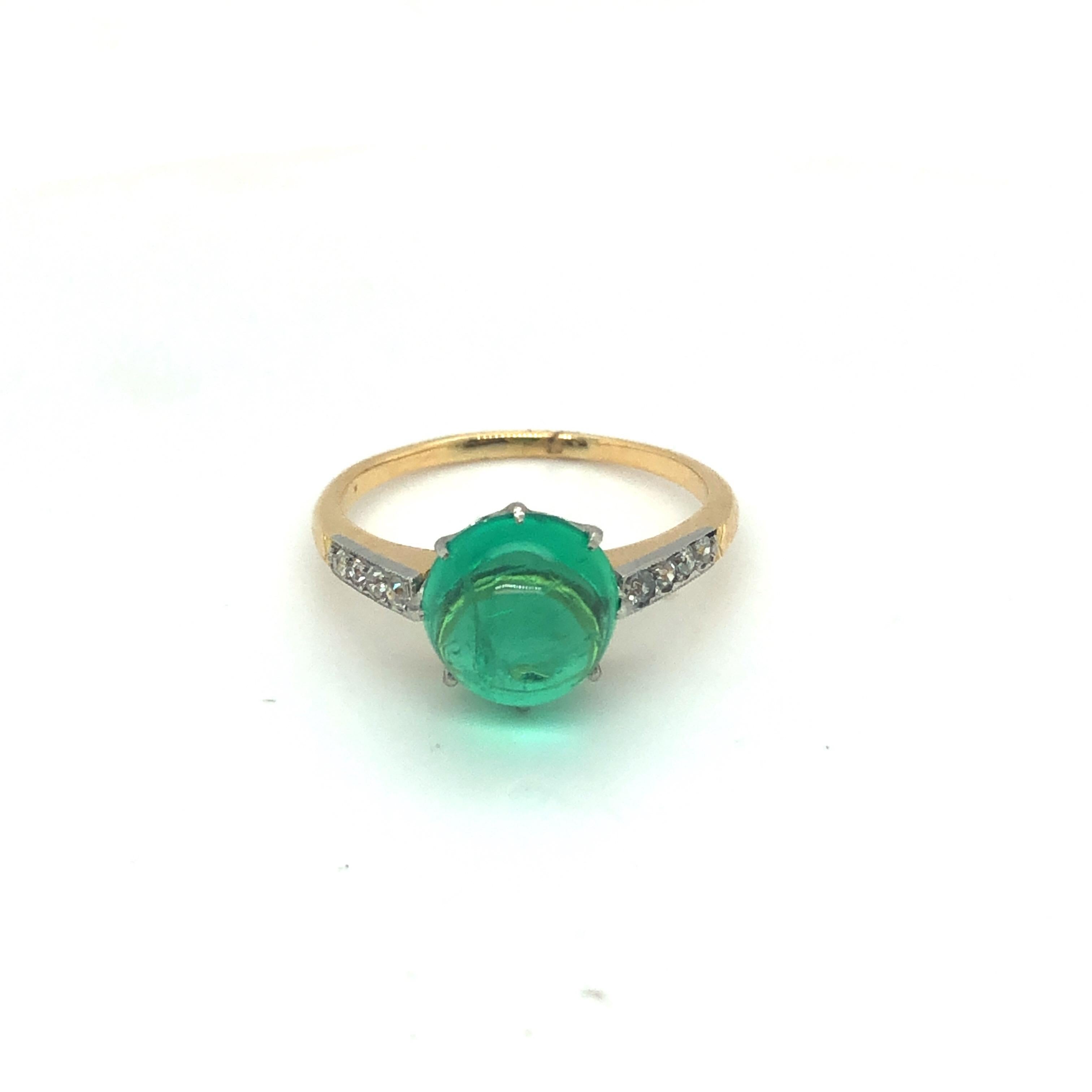 Exquisite 18 karat yellow gold, platinum, emerald and diamond ring, circa 1905.

This delicate ring is crafted in 18 karat yellow gold and platinum, centering upon a luminous Colombian emerald cabochon of circa 3.8 carats, flanked by 8 old-cut