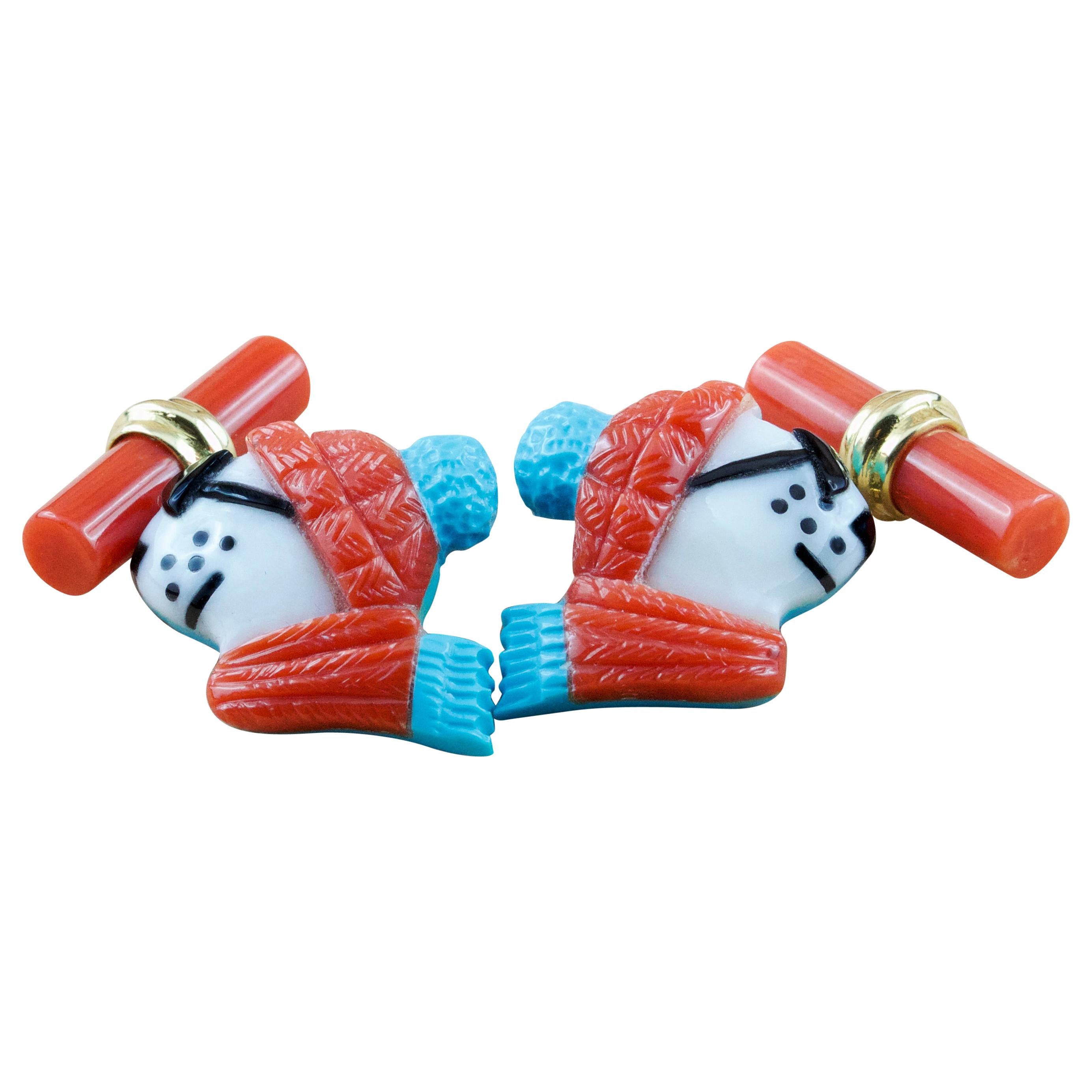 This playful pair of cufflinks depicts the profile of a polar bear portrayed as if dressed up for the winter with sunglasses, scarf, and hat. 
The animal is made of Mediterranean coral which is also used to make the cylindrical toggle, accents in