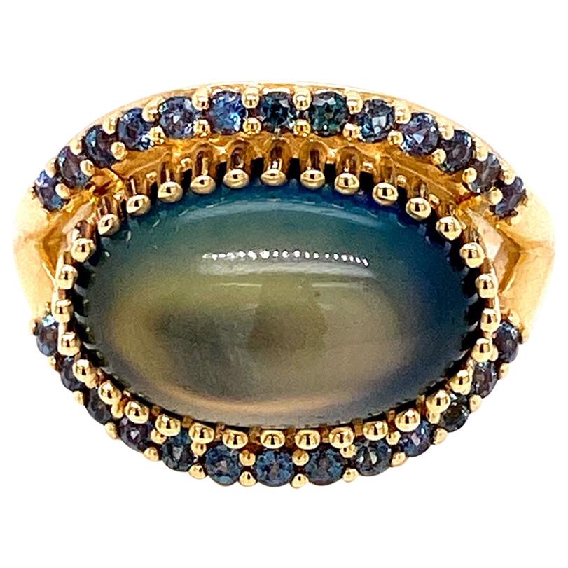 An 18k yellow gold ring set with a 6.09 carat rainbow moonstone cab with an onyx back (14.3mm x 9mm), and .53 carats of color change alexandrite. Ring size 7. This ring was made and designed by llyn strong.