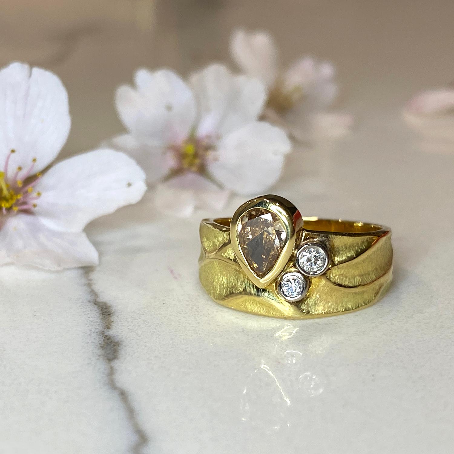La bague Rebecca en or jaune 18 carats, unique en son genre, est ornée d'un diamant brun de 0,46 carat rehaussé de deux diamants blancs (d'un poids total de 0,07 carat) sertis dans de l'or blanc au palladium 18 carats. L'anneau contemporain mesure