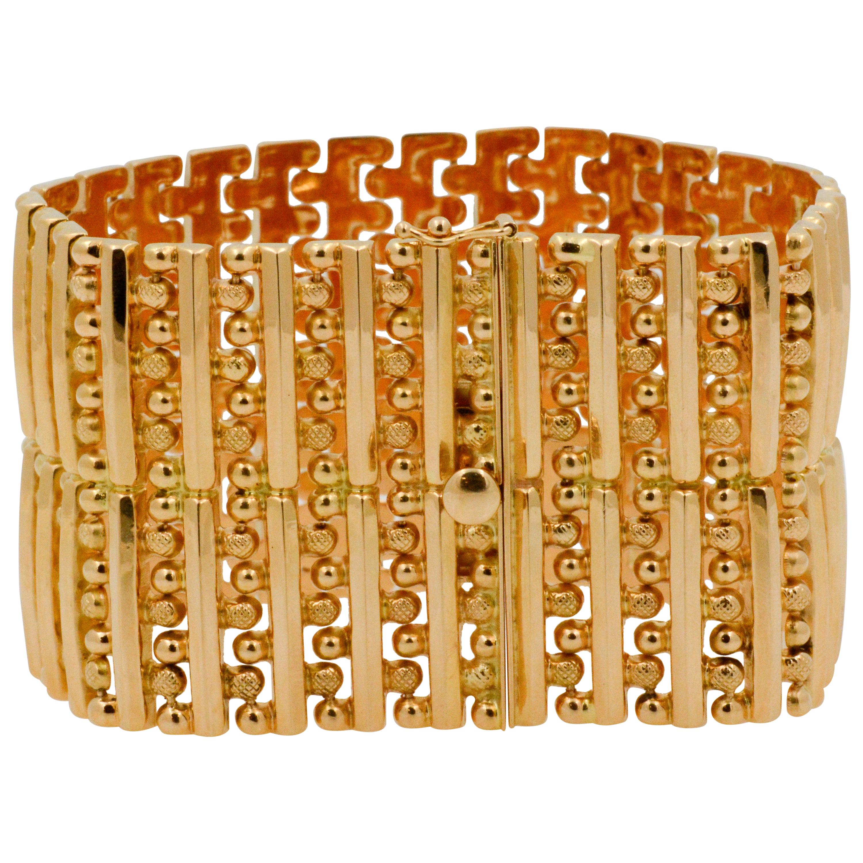 This retro bracelet showcases a 1 and 5/8” wide two row 18k yellow gold band with 29 polished bars and polished beads. The back of the bracelet is polished with a puzzle pattern and is 7.5” long. 