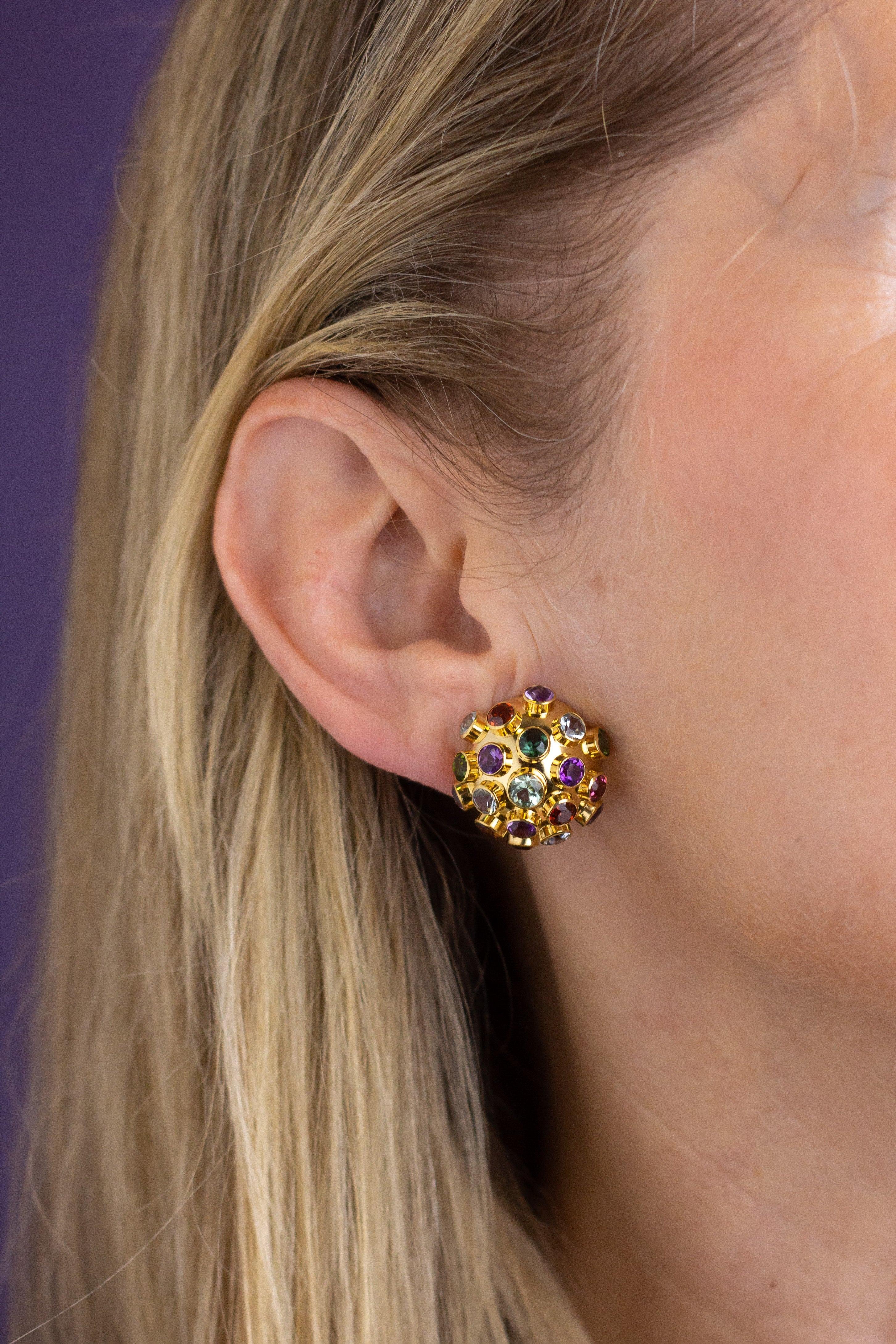 This pair of 18 karat yellow gold 'sputnik' ear clips were made by Brazilian designer H Stern during the mid 20th century. The domed 18 karat gold discs are rub-over set with an array of 38 semi precious stones including 12 amethysts, 10 topaz, 6