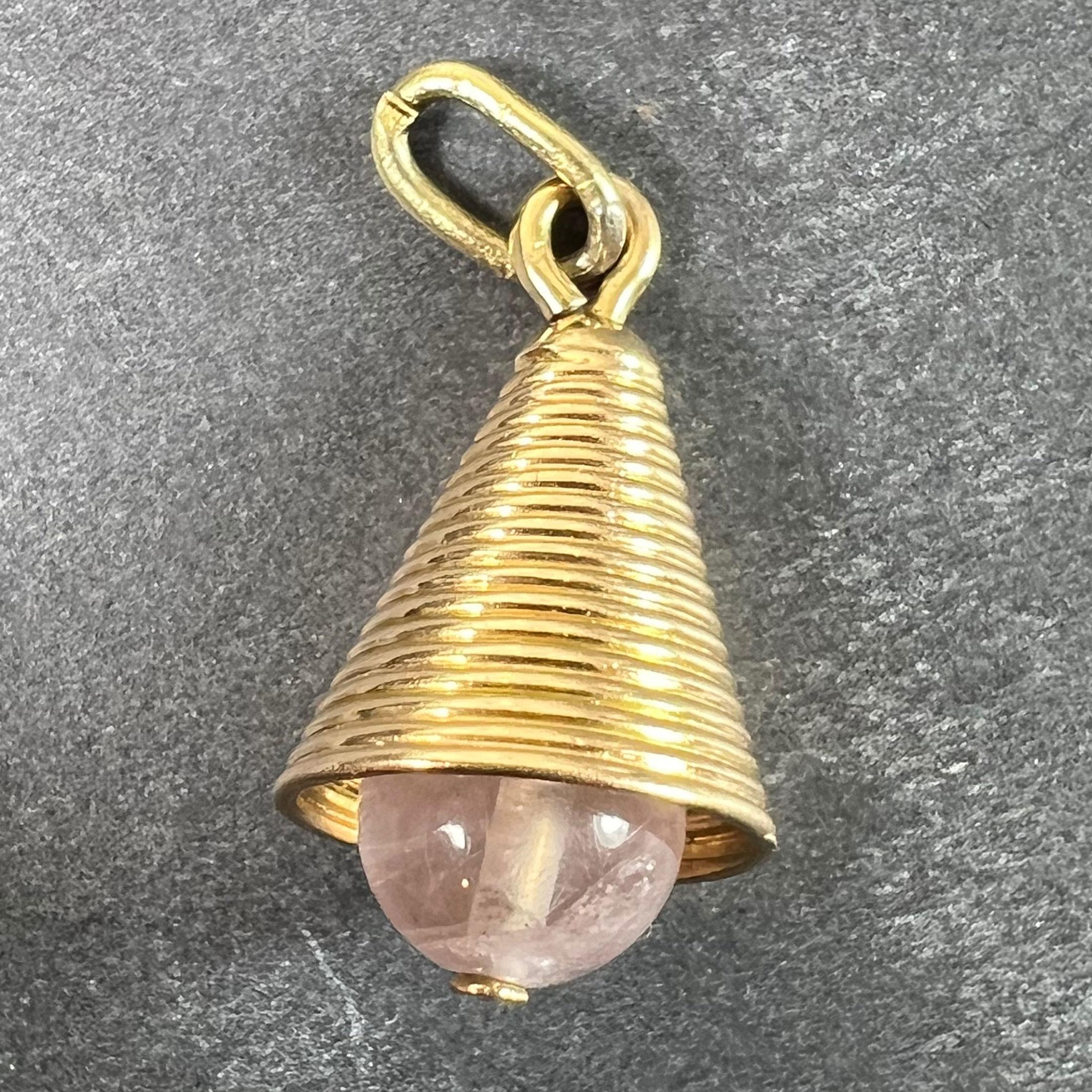 An 18 karat (18K) yellow gold charm pendant designed as a flaring bell with ridged decoration, mounted to the base with a spherical rose quartz bead. Unmarked but tested as 18 karat gold.

Dimensions: 2.1 x 1.2 x 1.2 cm (not including jump