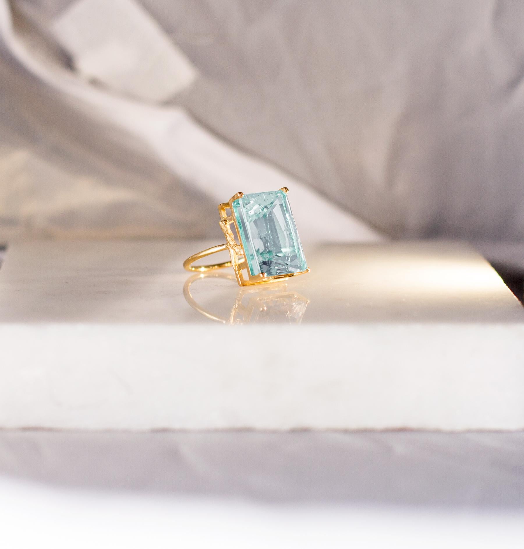 This engagement ring features a neon copper bearing Paraiba tourmaline (oval or cushion cut) set in 18 karat yellow gold. The exquisite neon color of the gem catches the eye and is accentuated by the fine jewelry work of tiny prongs. This ring can