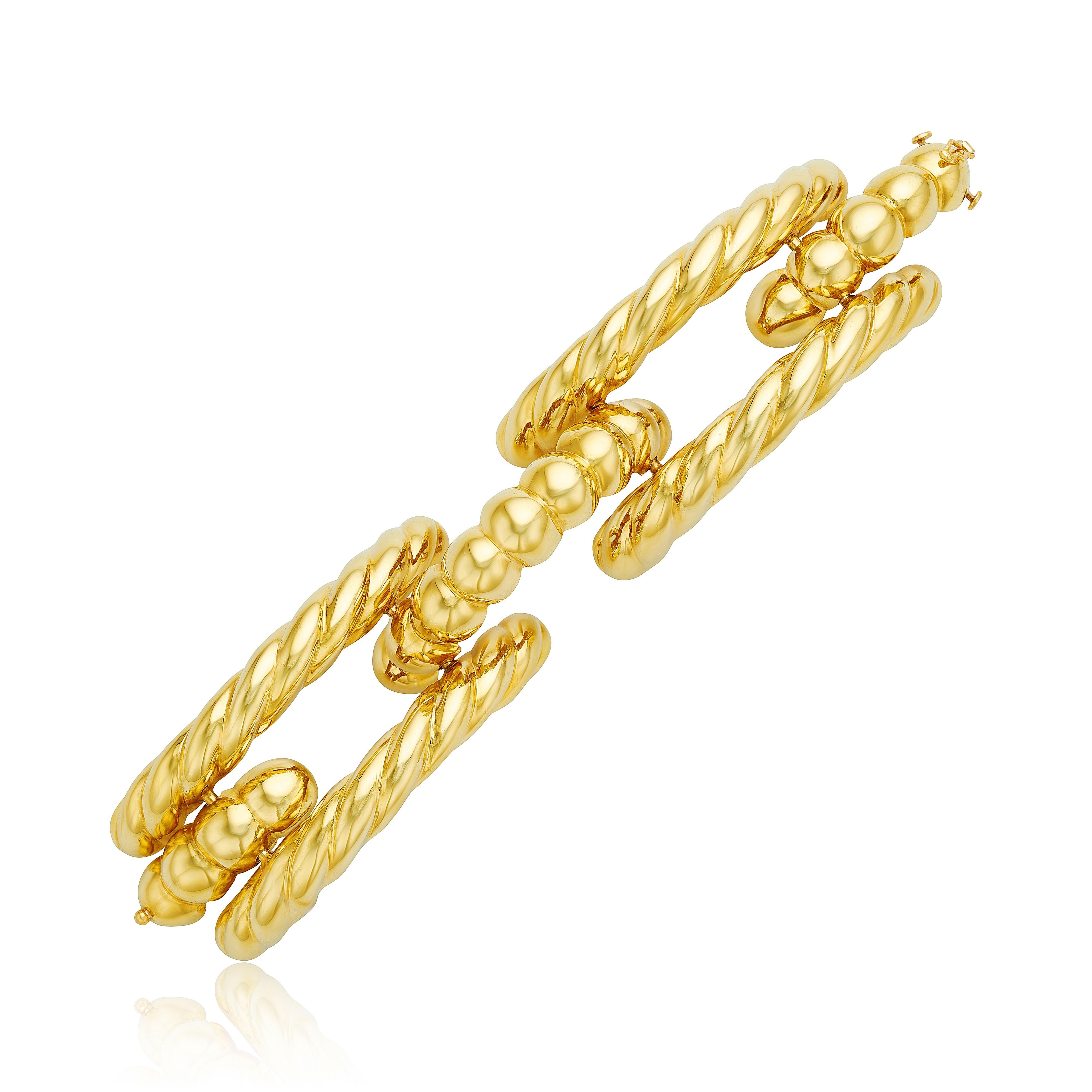 With an intricate robe texture design, this 18 karat yellow gold bar bracelet is unique in its three tier design that leaves a slight opening in the middle. 