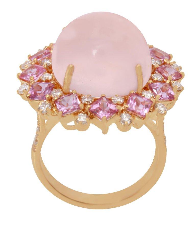 This beautiful ring has a 13.75 carat Rose Quarts that is set in the center of the ring and has 12 Square shape Pink Sapphires that weigh 2.52 carats. This ring also has 32 Round Cut Diamonds that weigh 0.78 carats and are set along the shank of the