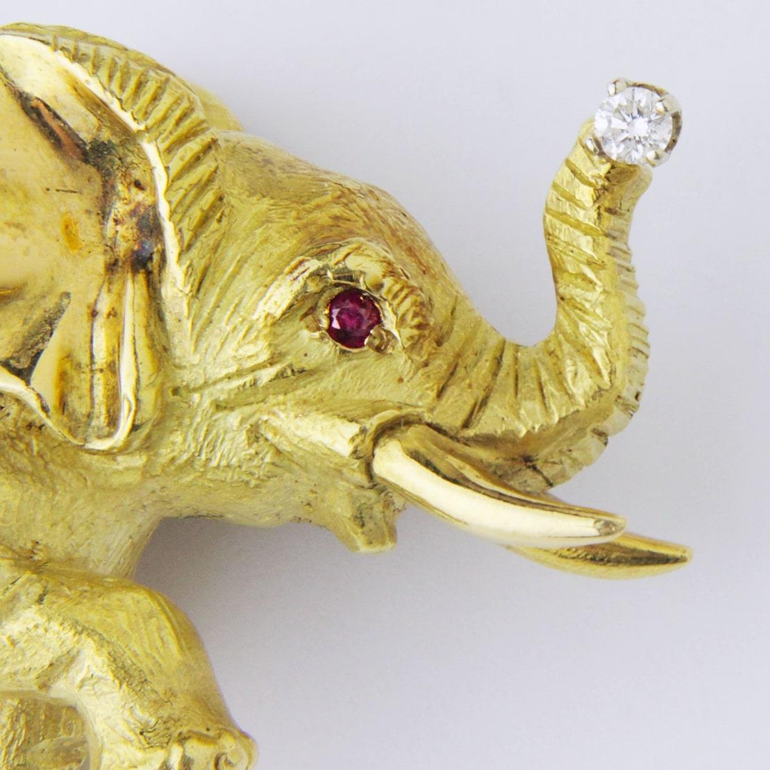 Add a touch of whimsy to your ensemble with this 18kt yellow gold elephant brooch pin, featuring a brilliant cut ruby, and a 0.07ct brilliant cut diamond. The piece has a hinged pin and secure roller clasp which is working well. The matte Florentine