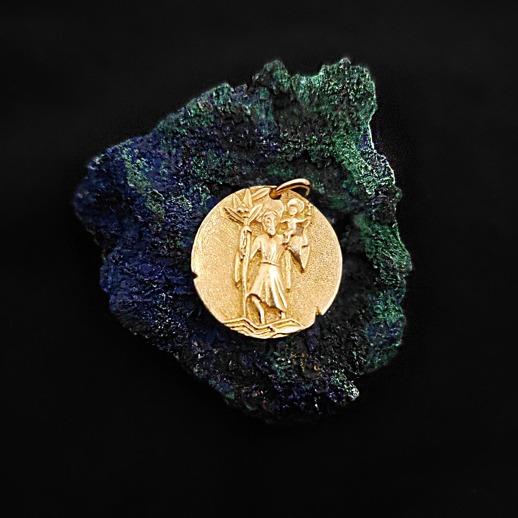 A travelers keepsake. This Saint Christopher medallion  pendant is crafted in textured 18 karat yellow gold, fashioned after an ancient coin. 

One side of the pendant features a repoussé image depicting St. Christopher carrying the Christ child.